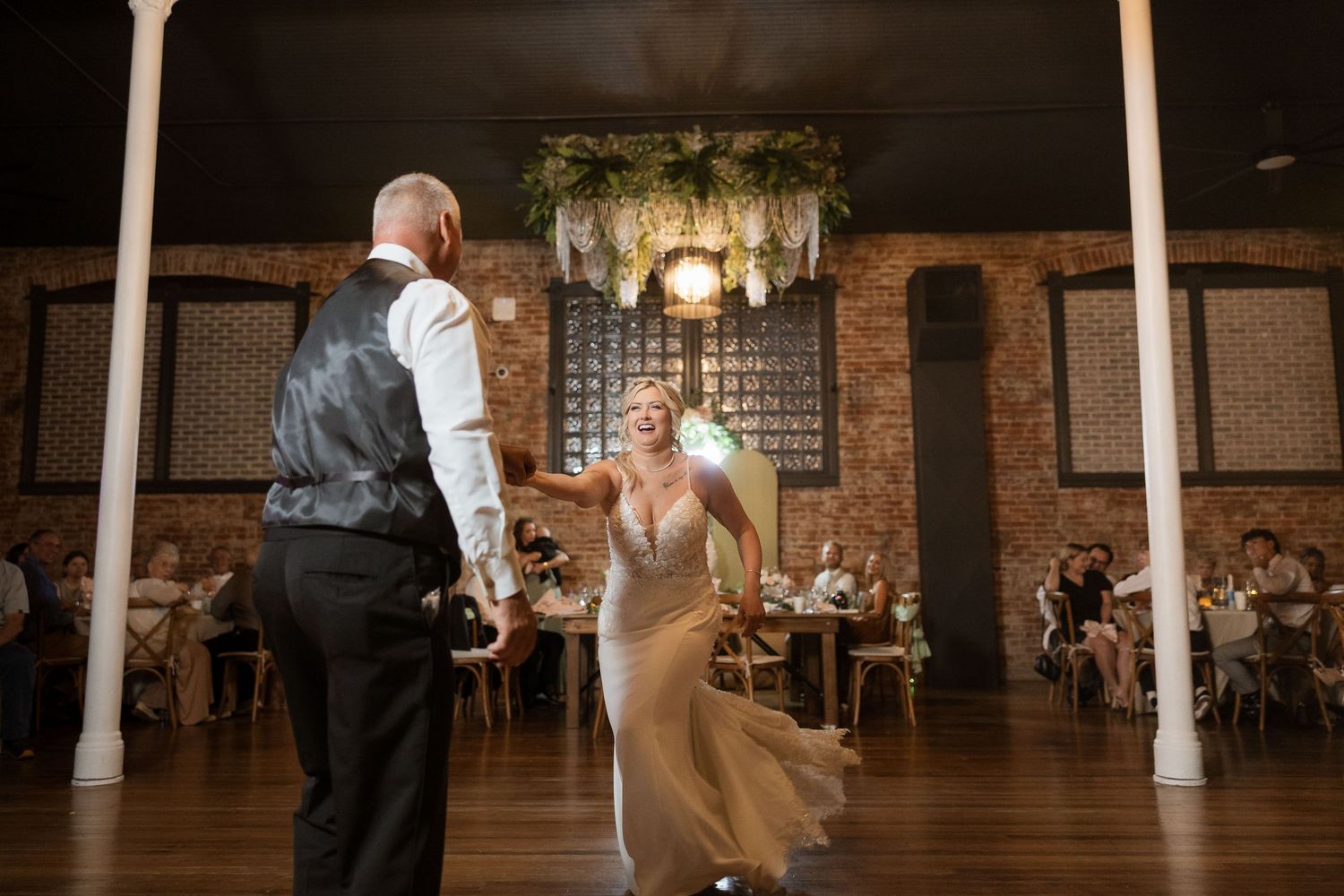Dark and moody wedding reception venue with exposed brick walls and decorative string lights.