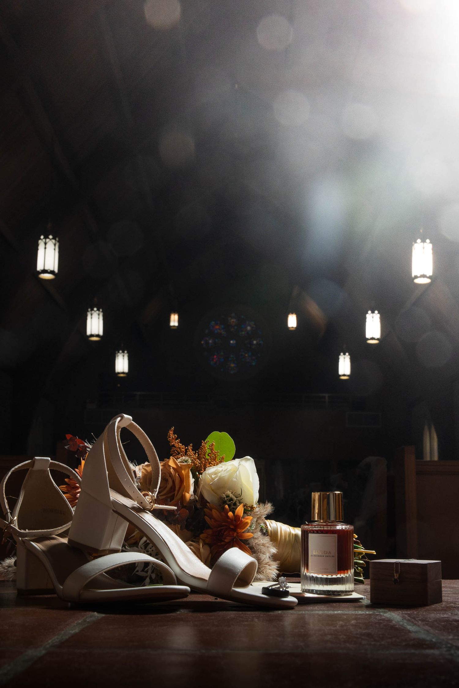 Wedding shoes and accessories artistically lit against dark background with hanging lanterns.