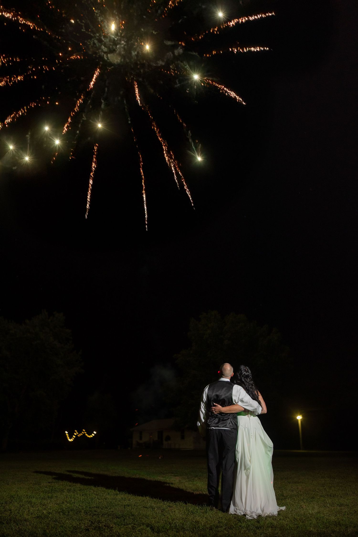 A couple watches fireworks display together during an outdoor evening celebration.