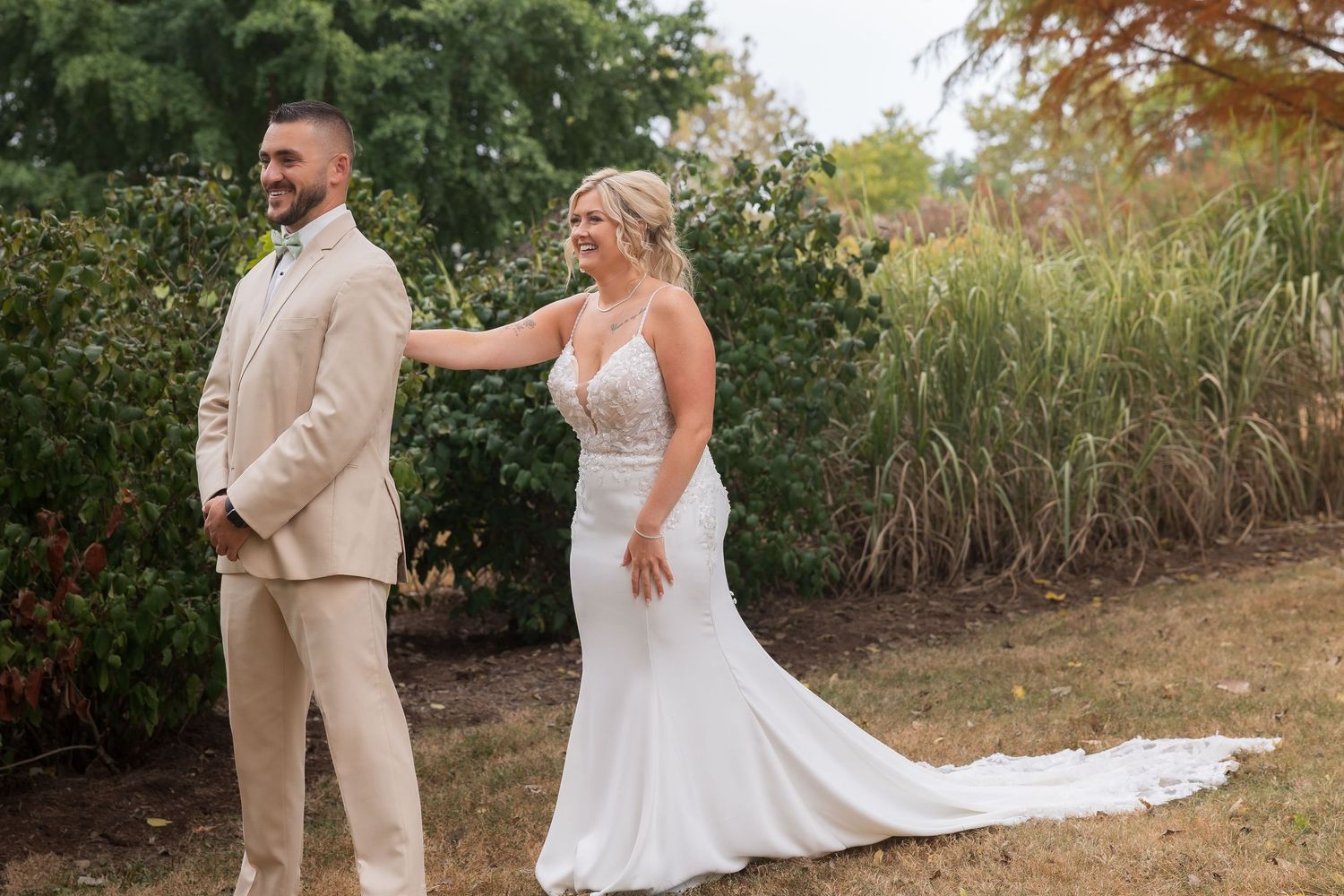 First look wedding moment captured in outdoor garden setting with fall foliage.