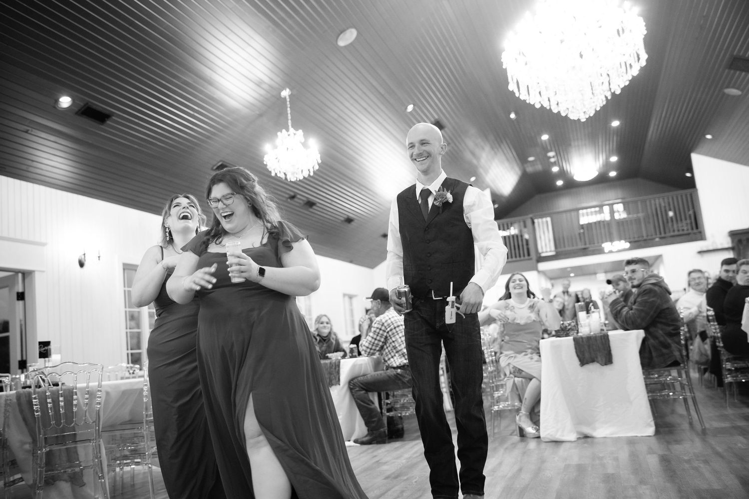 Wedding reception guests dancing and celebrating under elegant crystal chandeliers in an indoor venue.