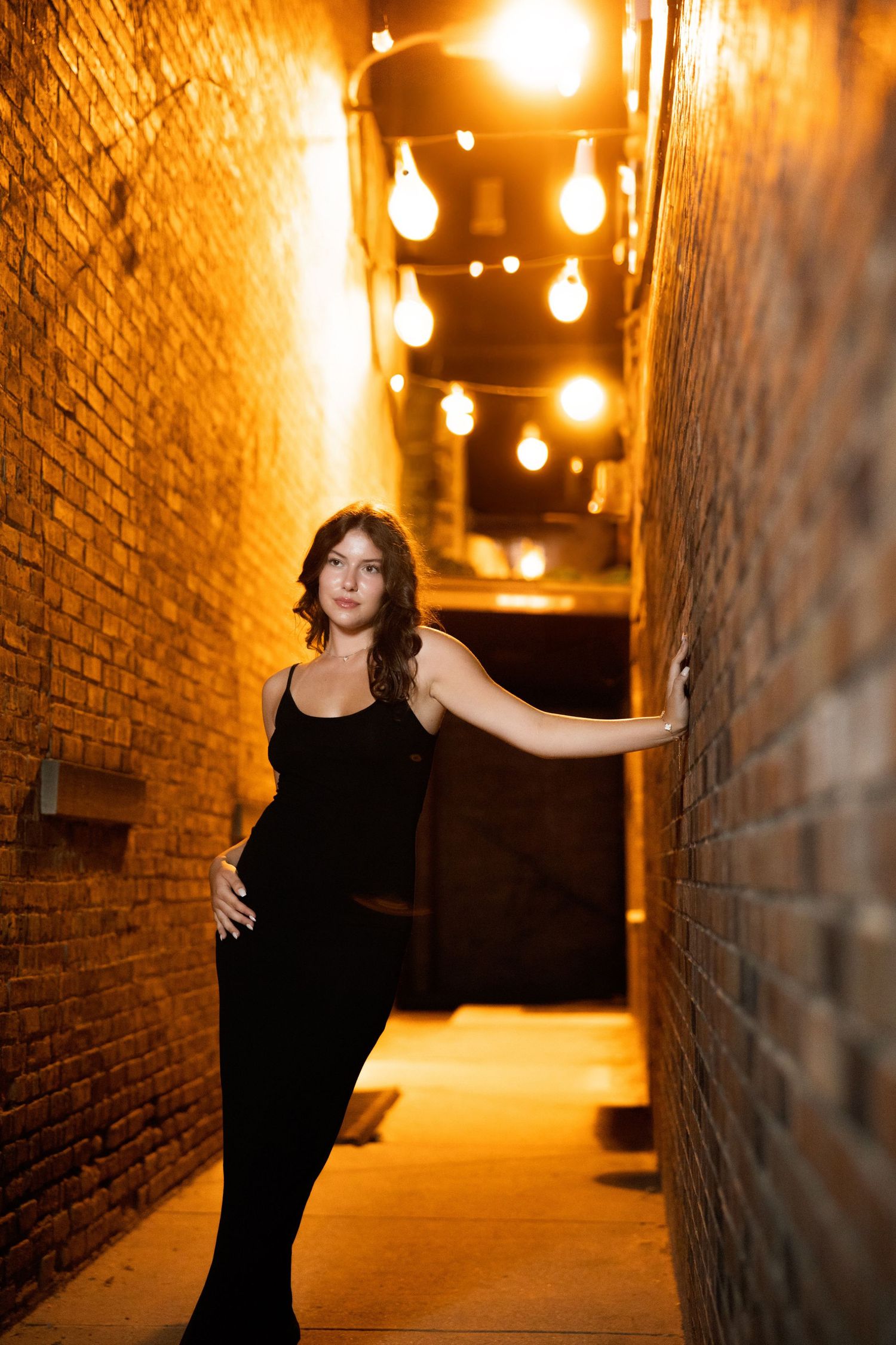 Dimly lit brick alleyway with warm string lights creating moody ambiance.