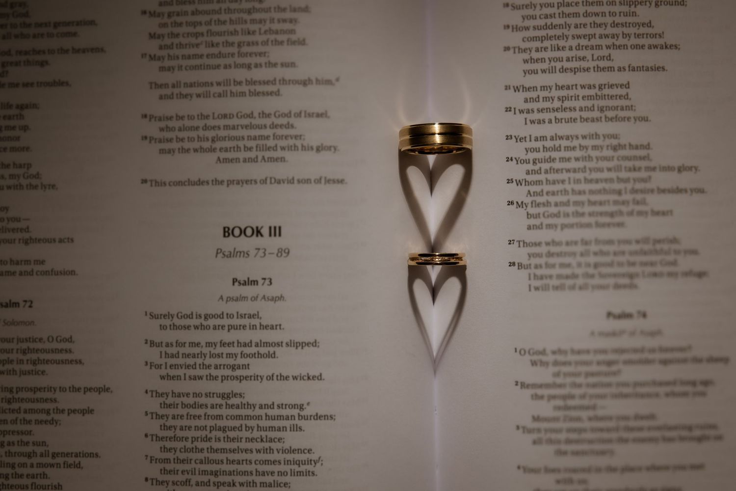 Wedding rings cast heart-shaped shadow on ceremony program pages.