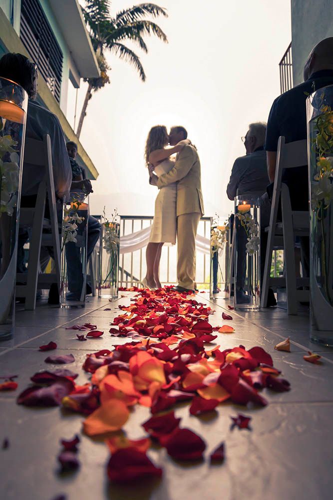 Red rose petals scattered on a white floor create a romantic pathway at sunset.