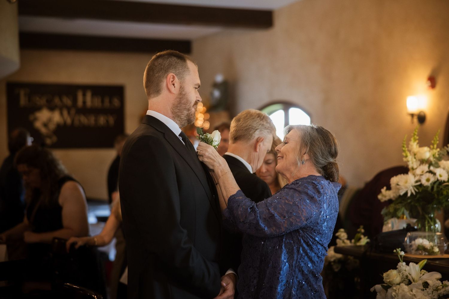 Couple in formal attire dancing together at an elegant indoor reception venue with warm lighting and wooden beams.
