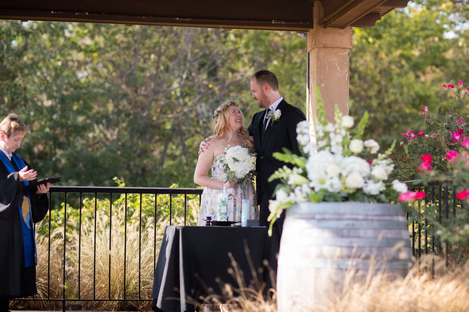 Wedding ceremony setup with white chairs and floral arrangements under covered patio.
