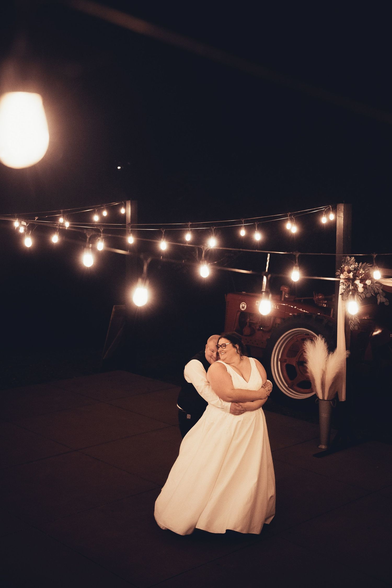 String lights illuminate a dark outdoor wedding reception space creating a magical ambiance.