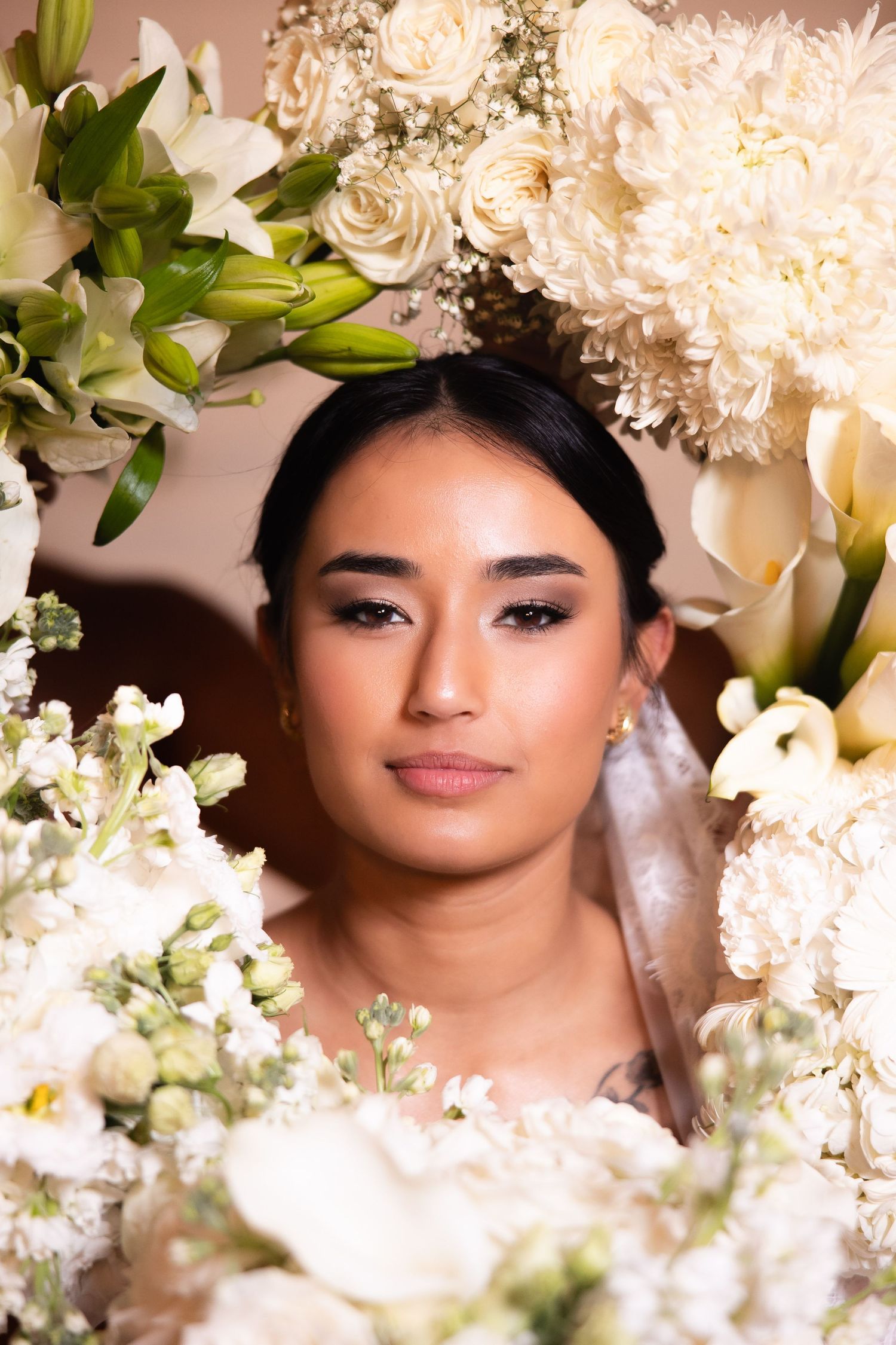 Dreamy bridal portrait surrounded by white flowers and soft lighting.
