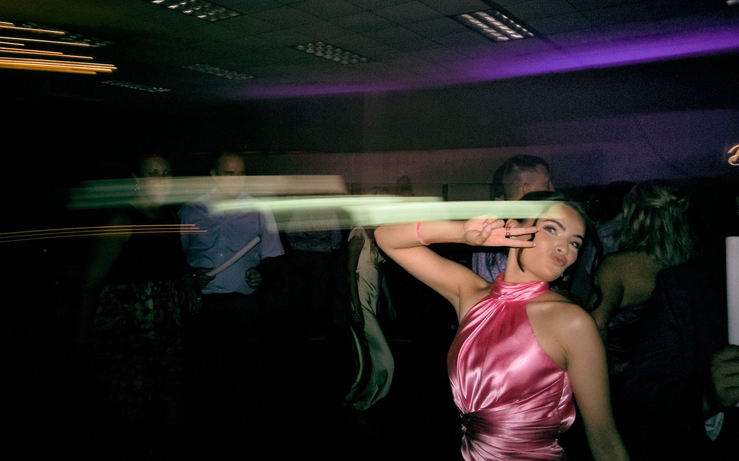 Woman in pink satin dress dancing at a nightclub party.