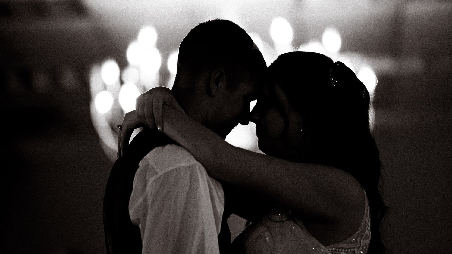 Romantic black and white photo of couple slow dancing at wedding reception.