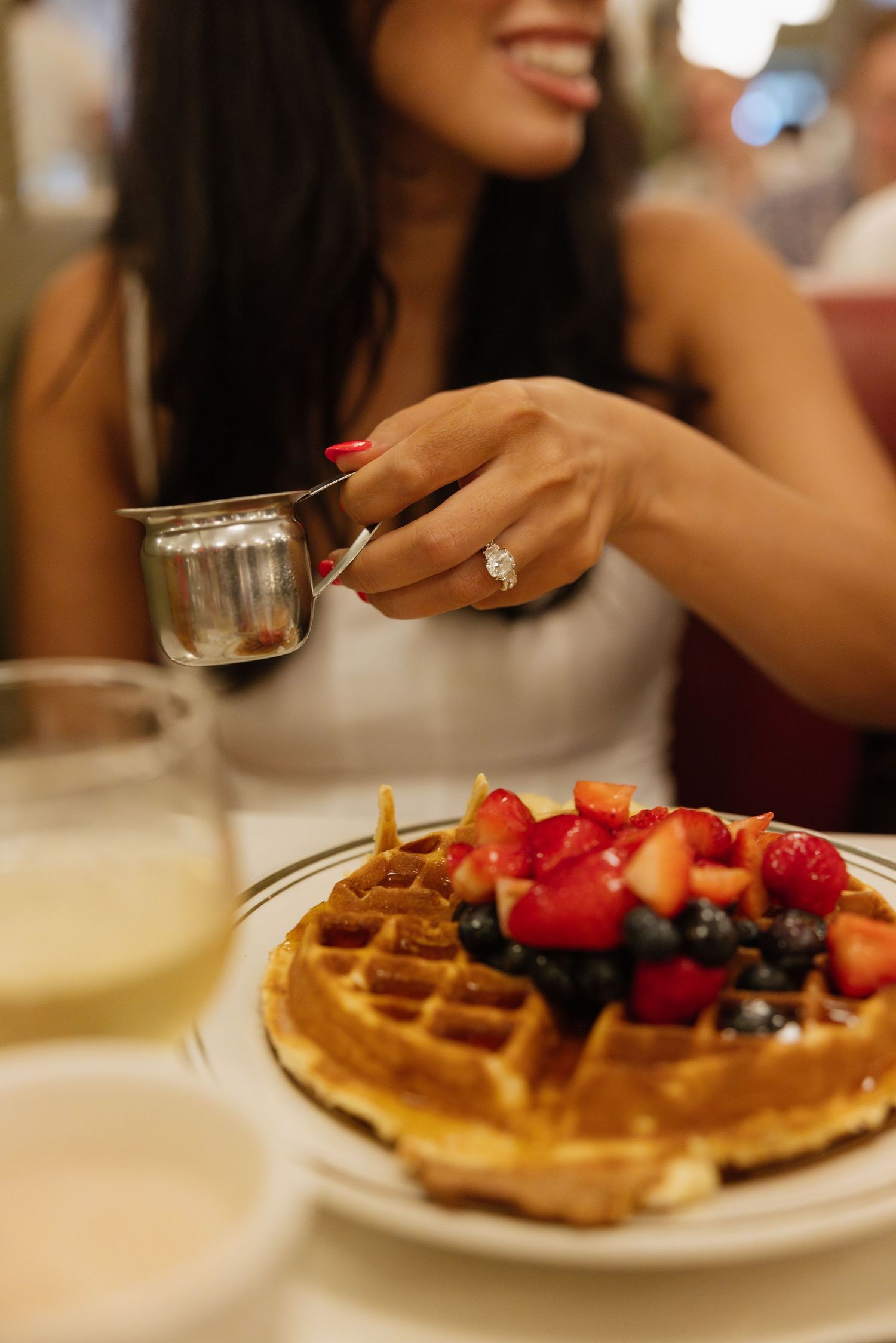 A sequence of photos showing fresh waffles topped with strawberries, blueberries and whipped cream on white plates.