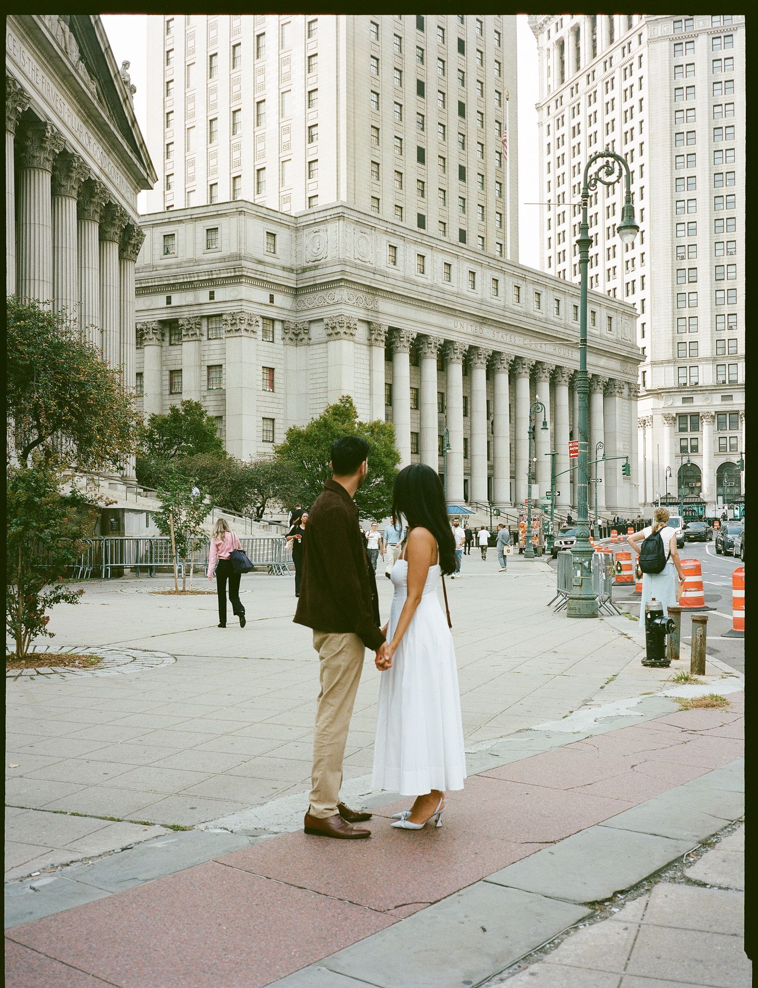 A sequence of five panoramic street photos showing a couple in formal attire posing along a city sidewalk near tall buildings.