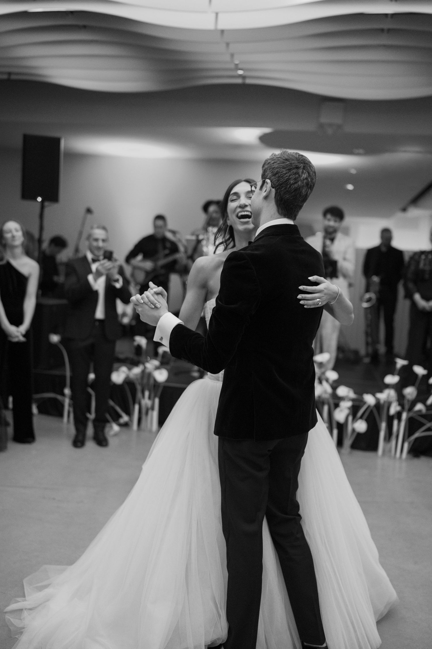 Black and white photo of a bride and groom sharing their first dance at a wedding reception.