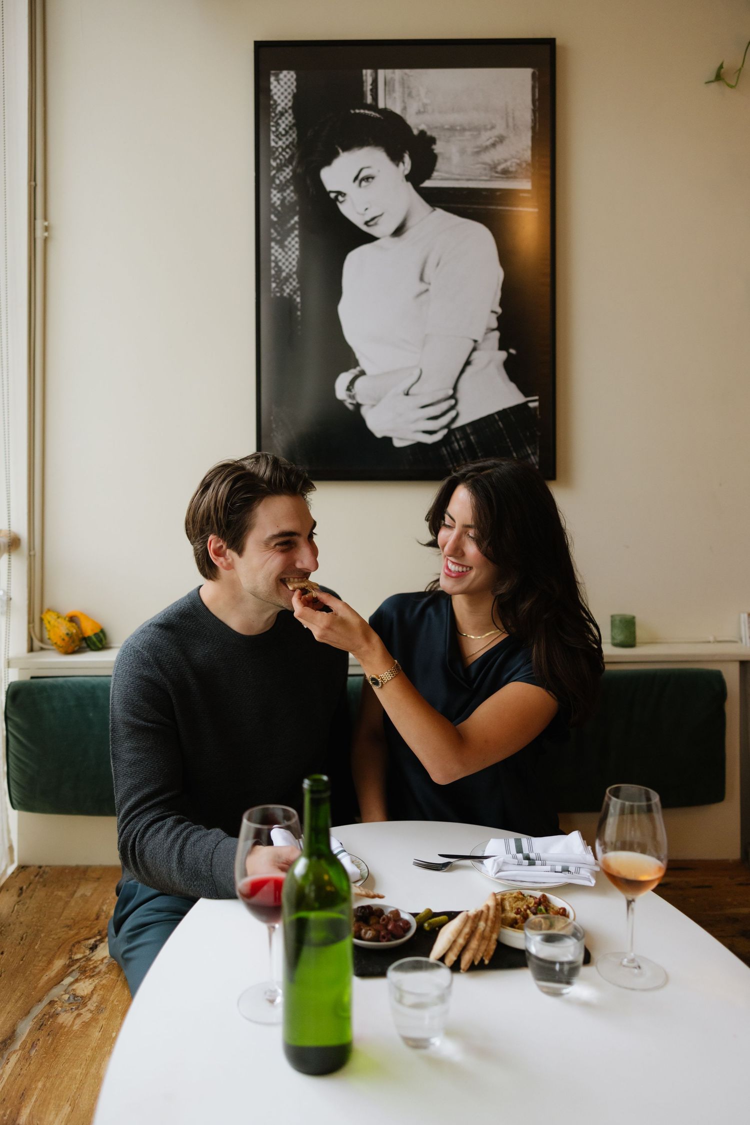 A couple shares a romantic meal at a restaurant table with wine and laughter in a series of candid moments.