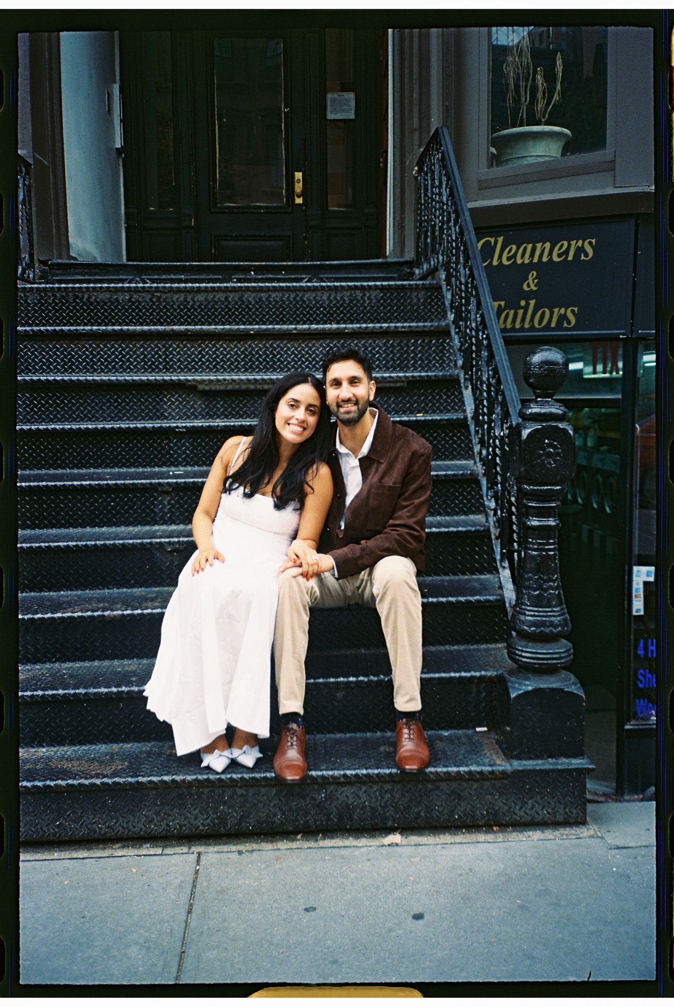 A couple sits together on city brownstone steps, creating a romantic urban moment in New York City.