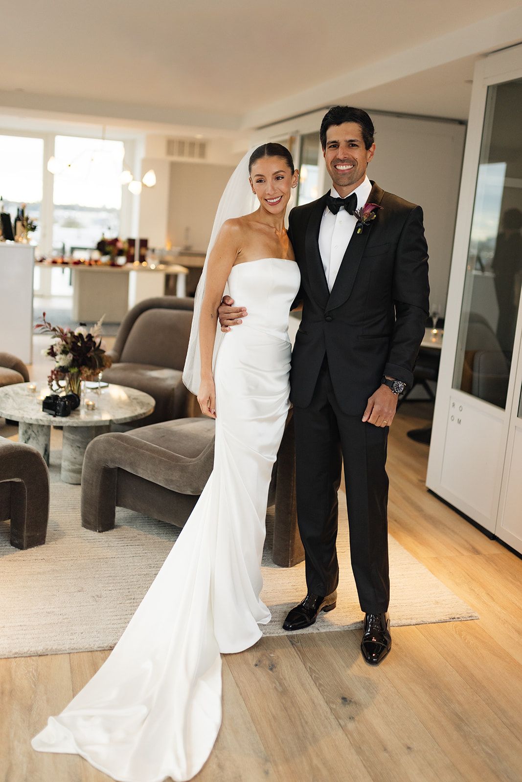 Wedding couple shares intimate moments in a contemporary living room with wooden floors and natural light.