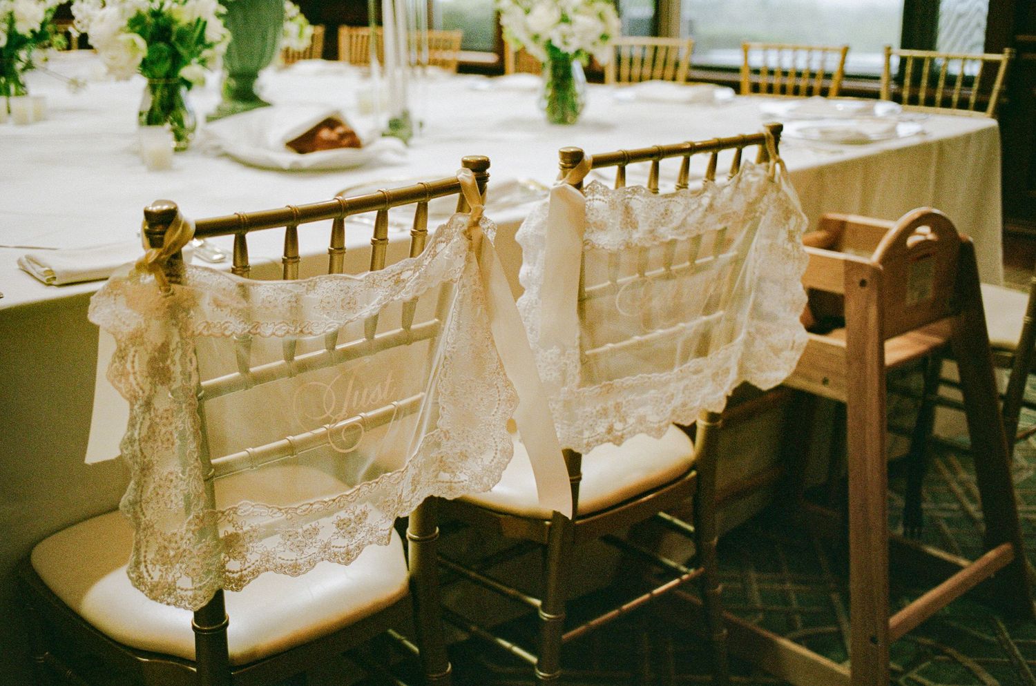 Gold Chiavari chairs adorned with elegant lace and ribbon sashes at a romantic wedding reception table setting.