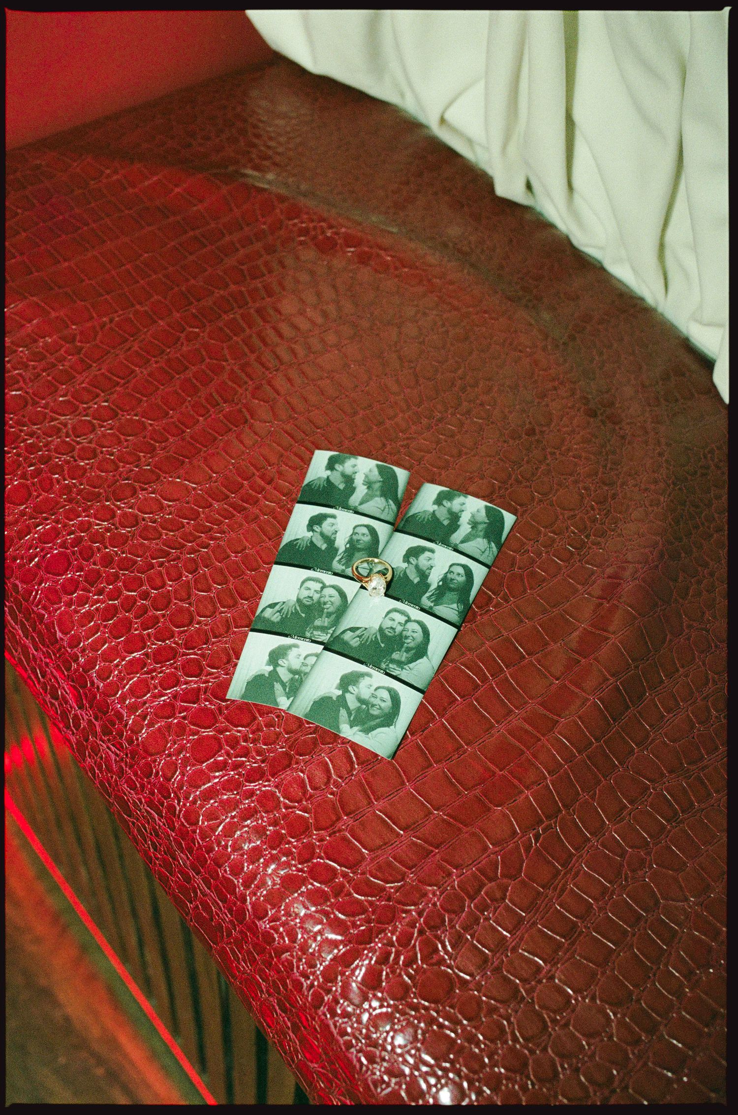 Red crocodile leather sofa with vintage photo booth strip pictures pinned on the armrest.
