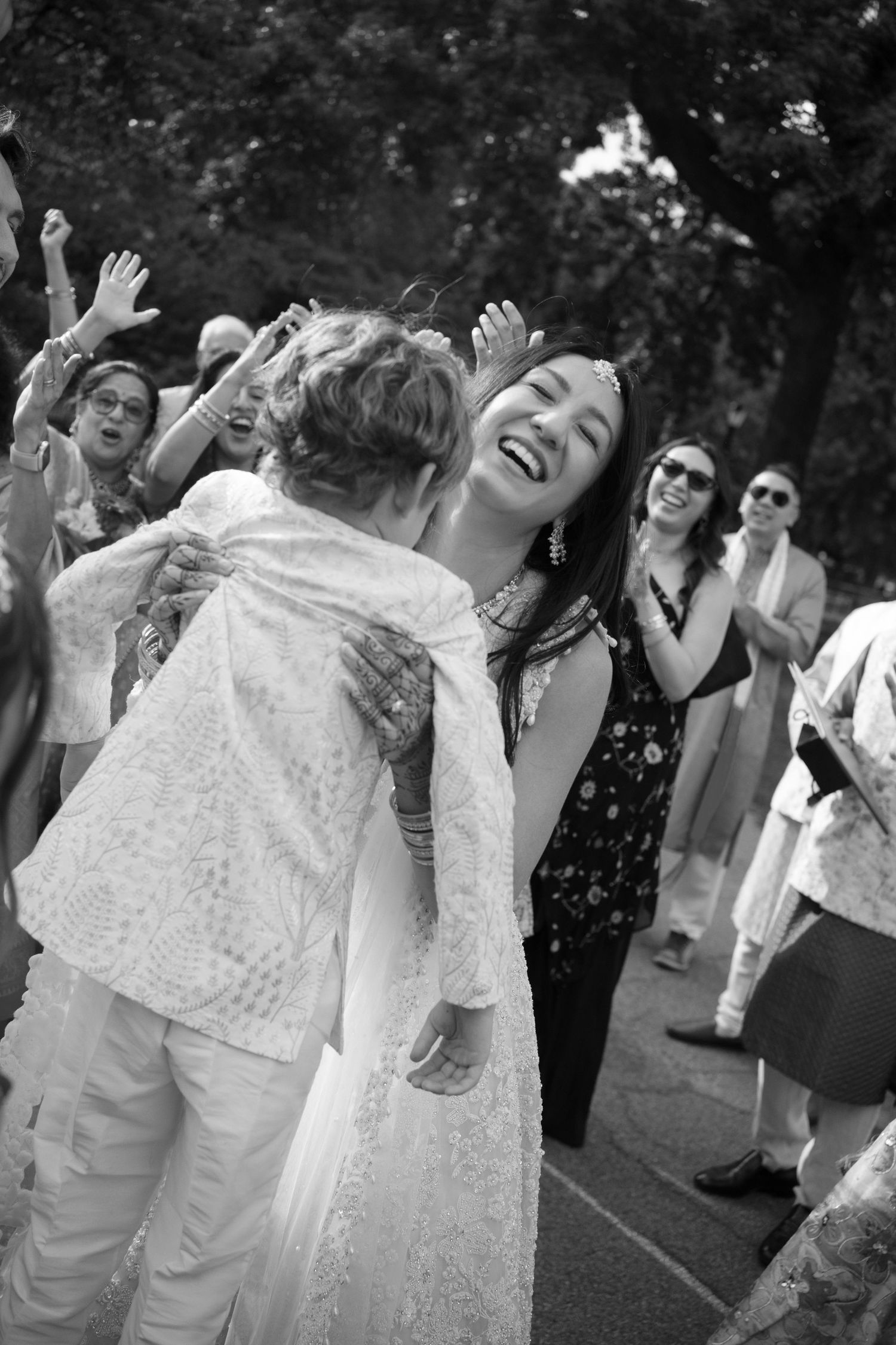 Black and white photo of joyful women dancing and celebrating outdoors at a festive gathering or wedding.