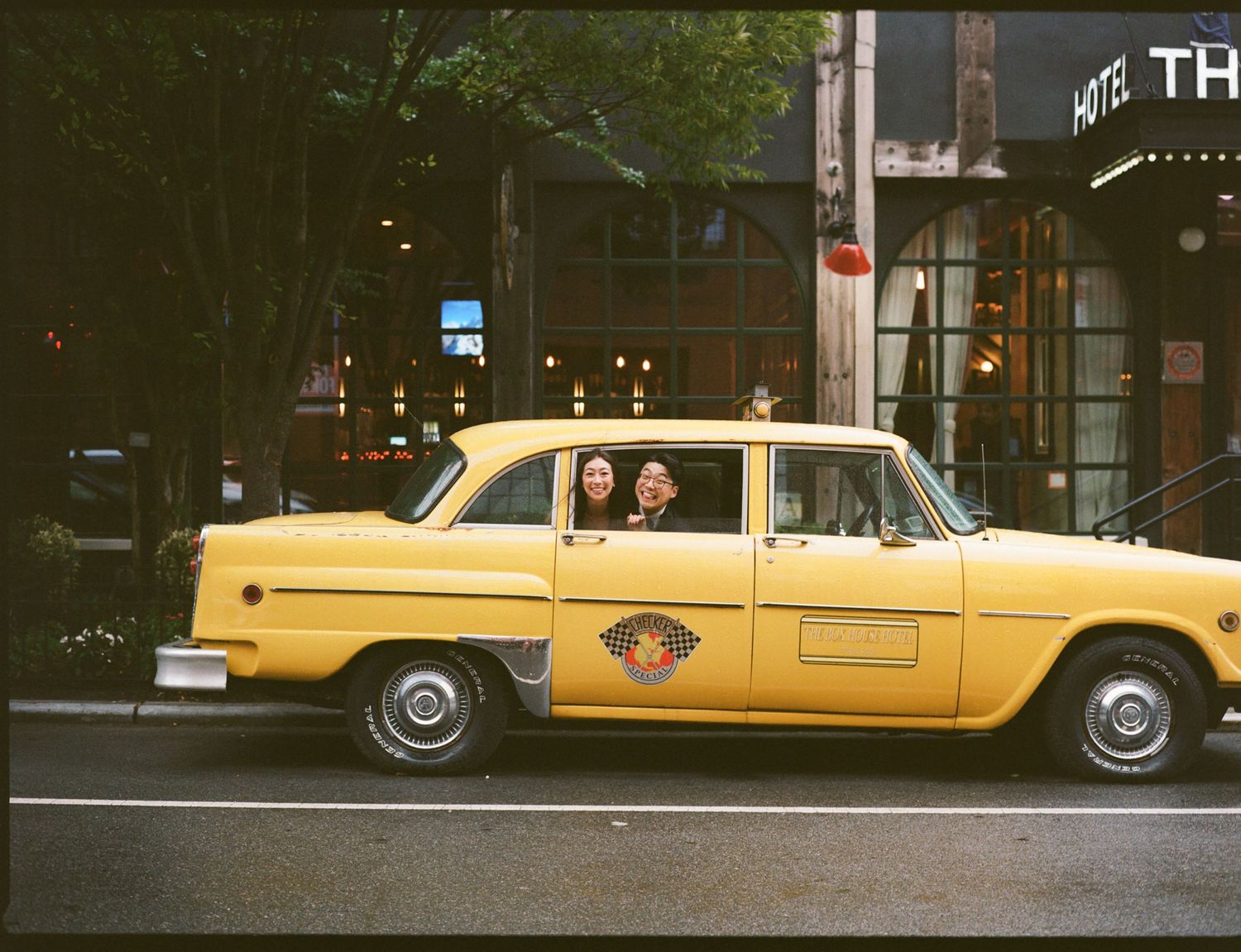 A yellow vintage taxi cab parked on a city street at night.