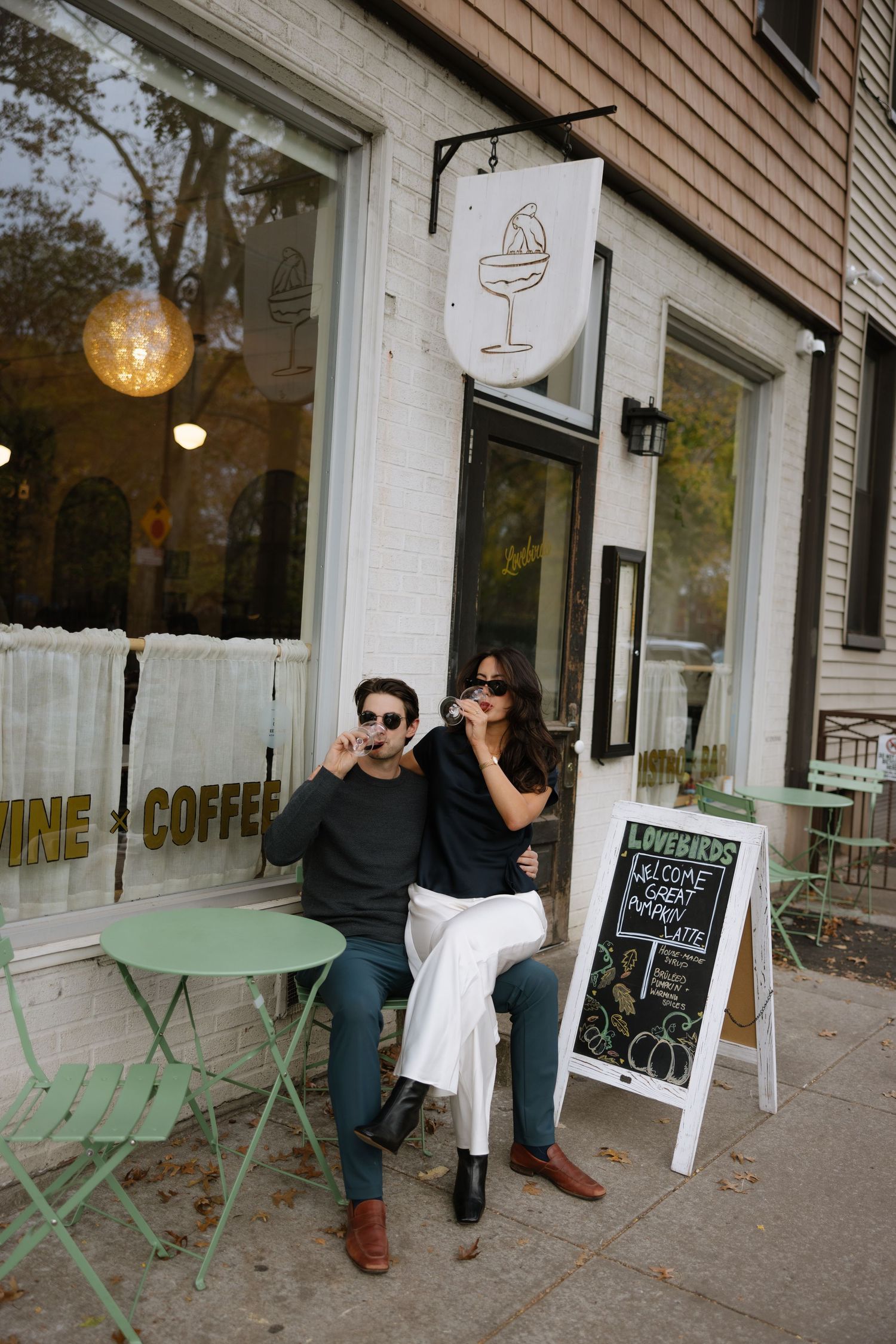 A cozy coffee shop storefront with mint green outdoor furniture and large windows creating a welcoming atmosphere.