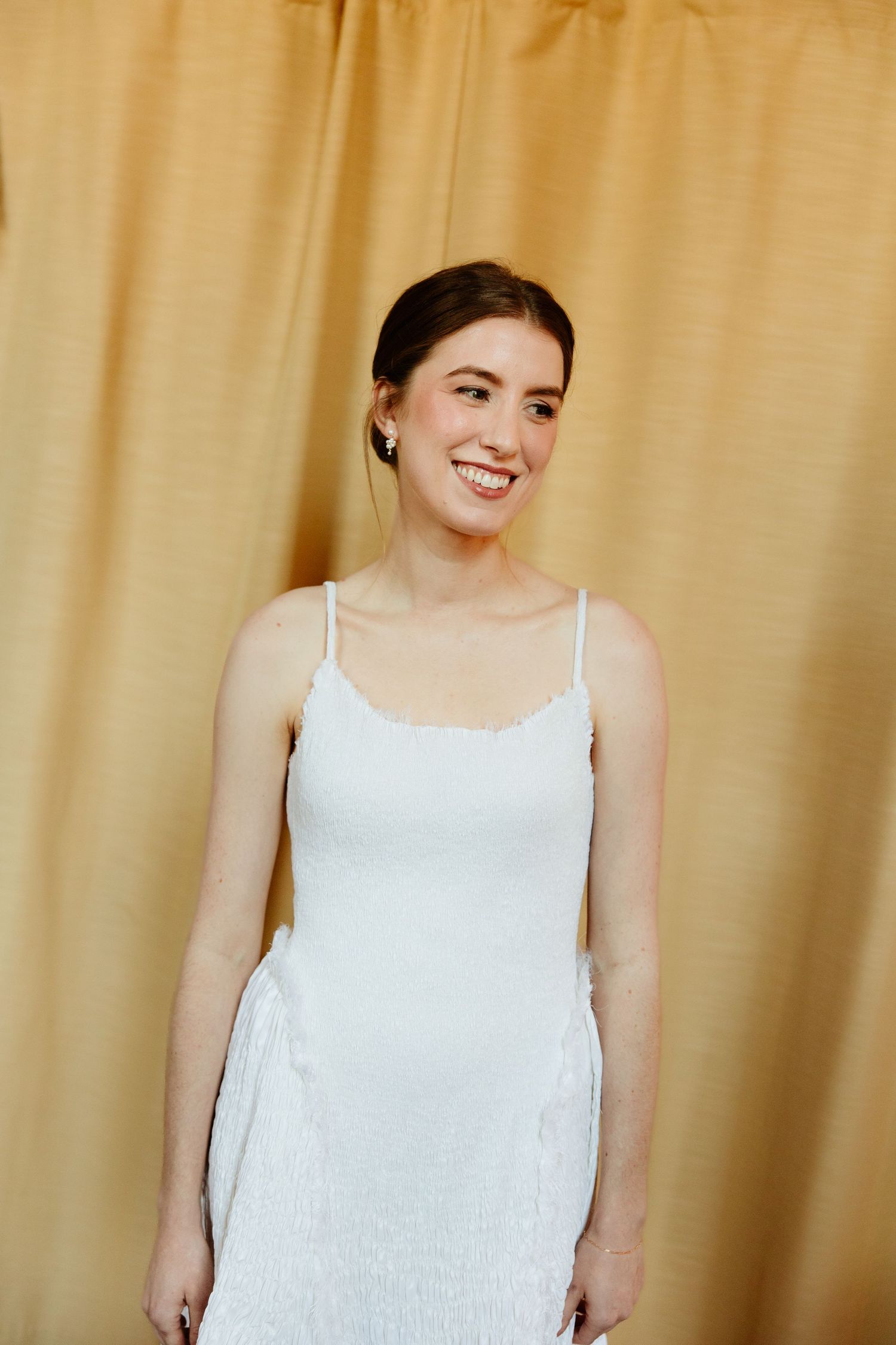 A series of photos showing someone wearing a white sleeveless top against a beige curtain background.
