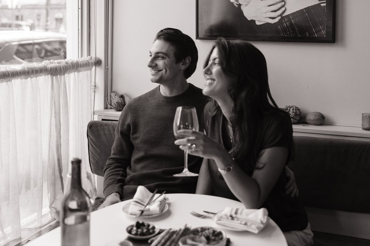 Two people enjoy a meal together at a restaurant table while sharing conversation and laughter.
