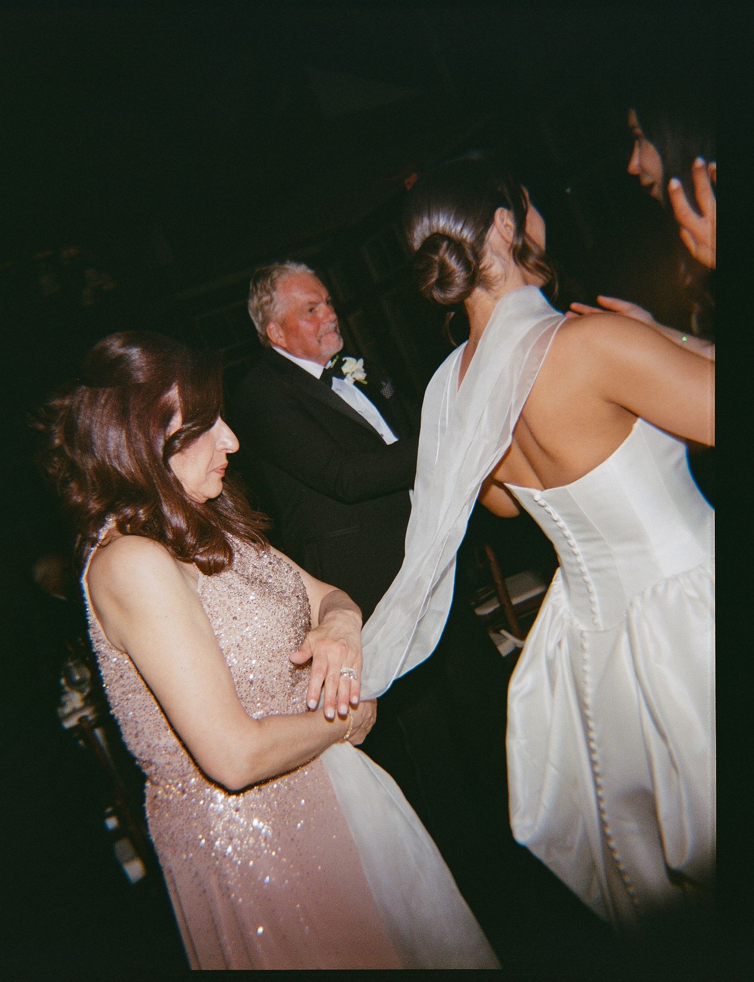 Bride in white gown dancing with guests in elegant attire at a wedding reception celebration.