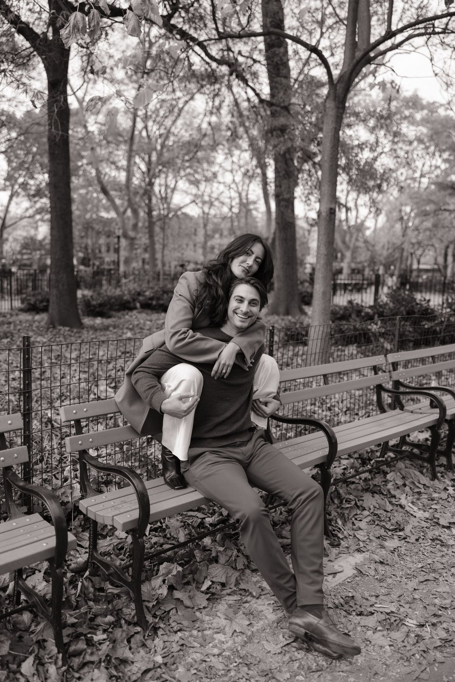 A person lounges playfully on a park bench in a series of black and white photos showing different relaxed poses.