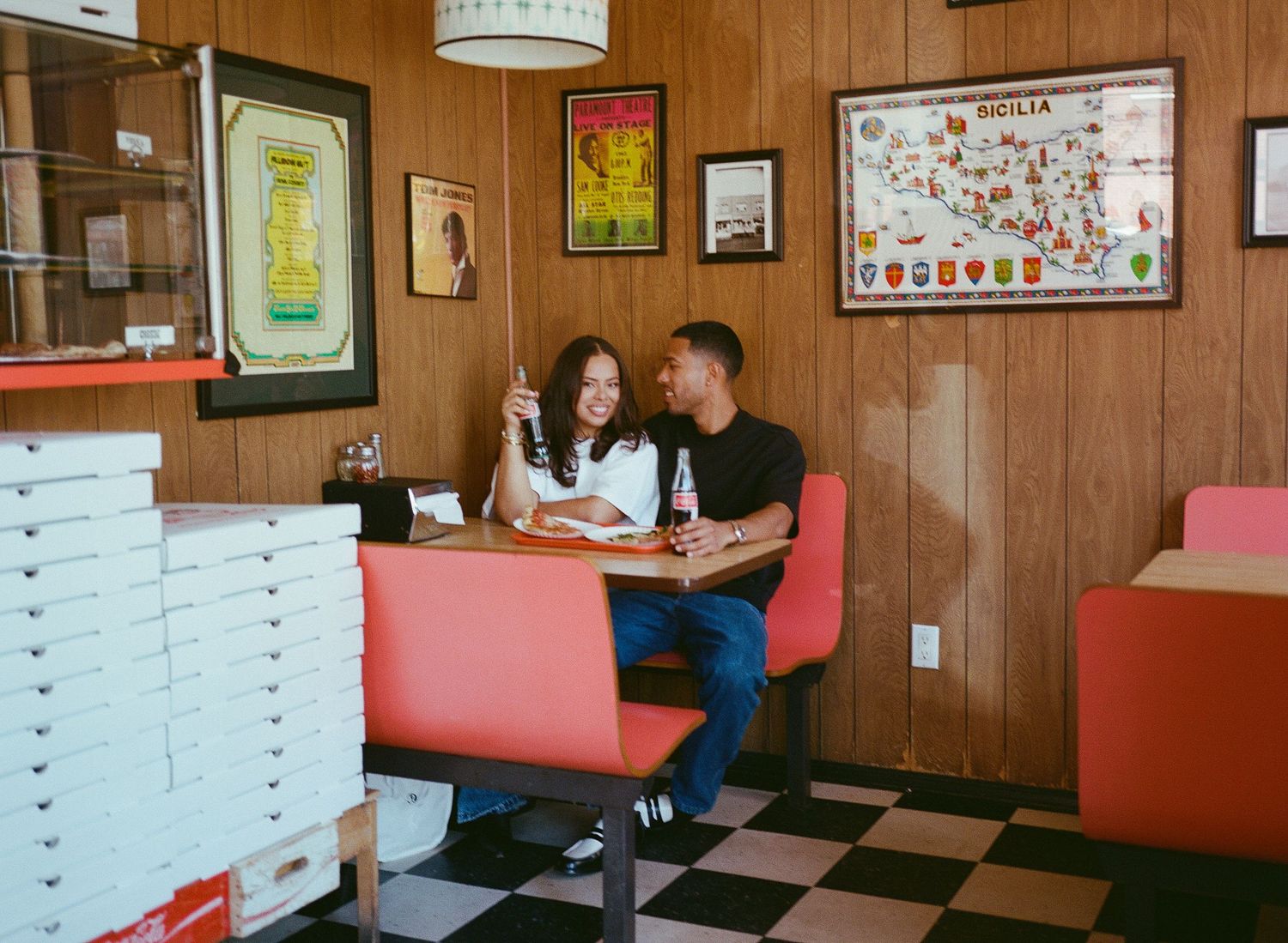 Panoramic view of a retro diner interior with wood paneling, red booth seating and vintage decor on the walls.