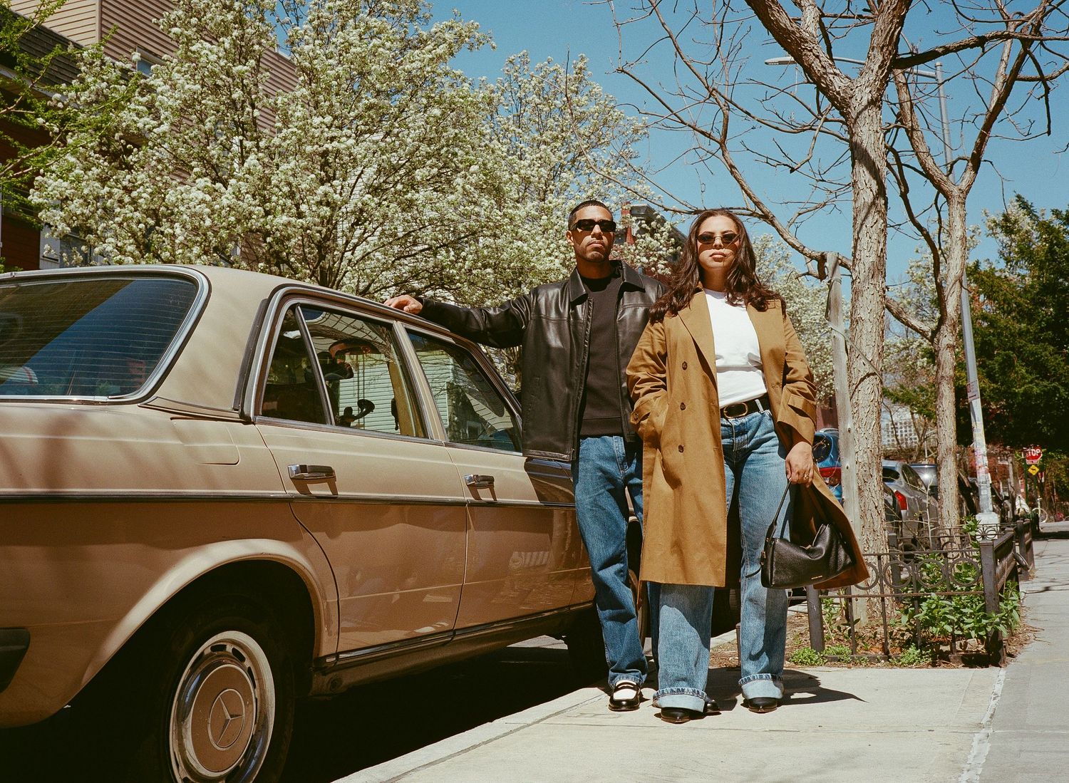 A series of connected photos showing people posing with a vintage brown car under blooming spring trees.