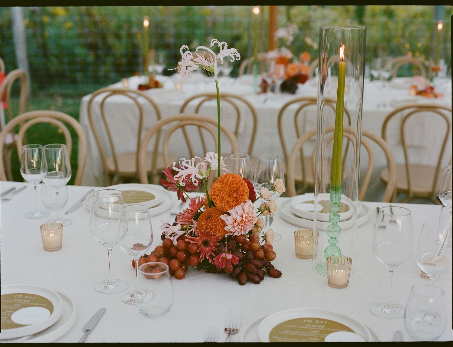 Elegant wedding reception tables decorated with orange floral centerpieces, white linens and gold accents.
