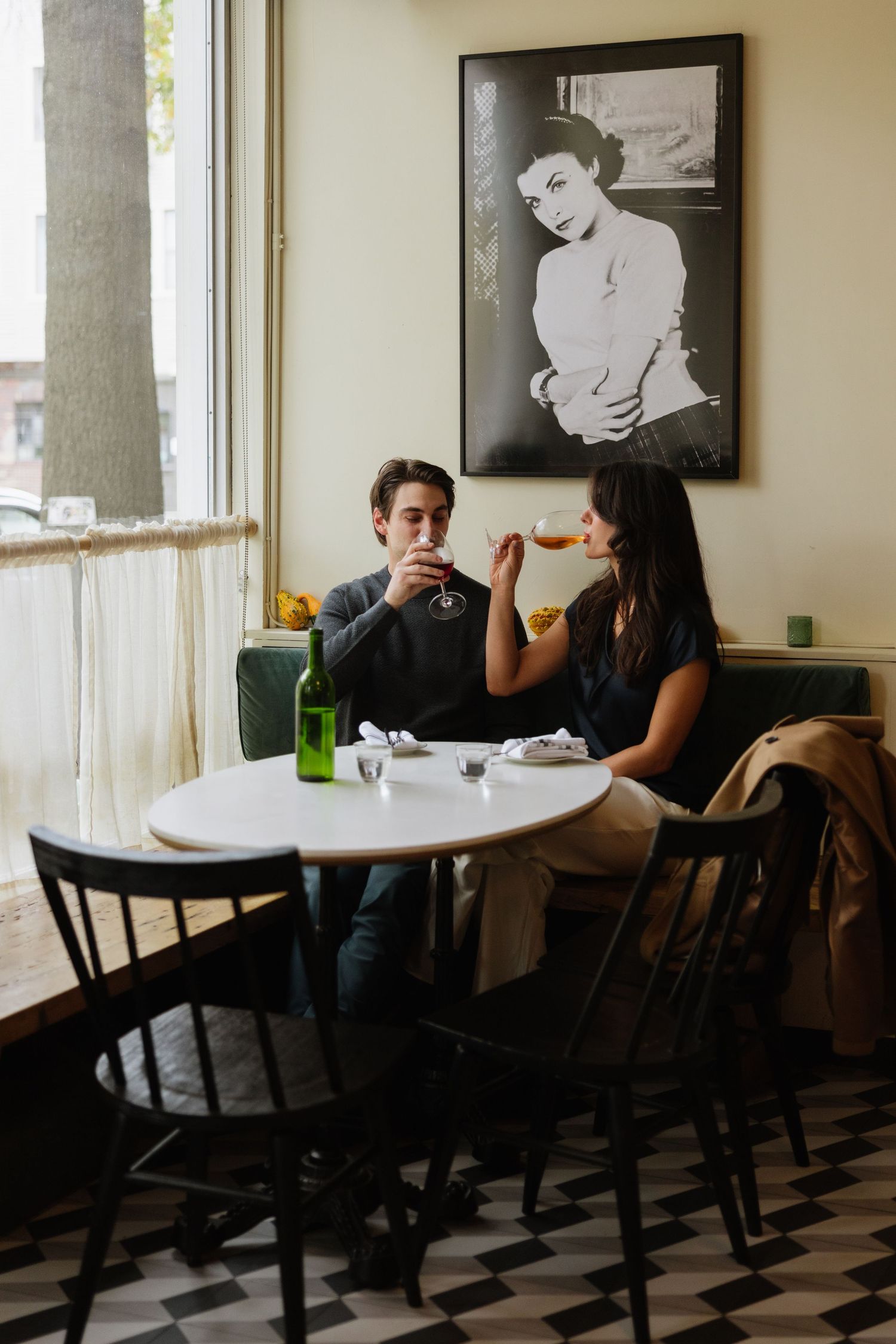 Two people sit at a round white table in a dimly lit cafe with vintage black and white photos on the wall.