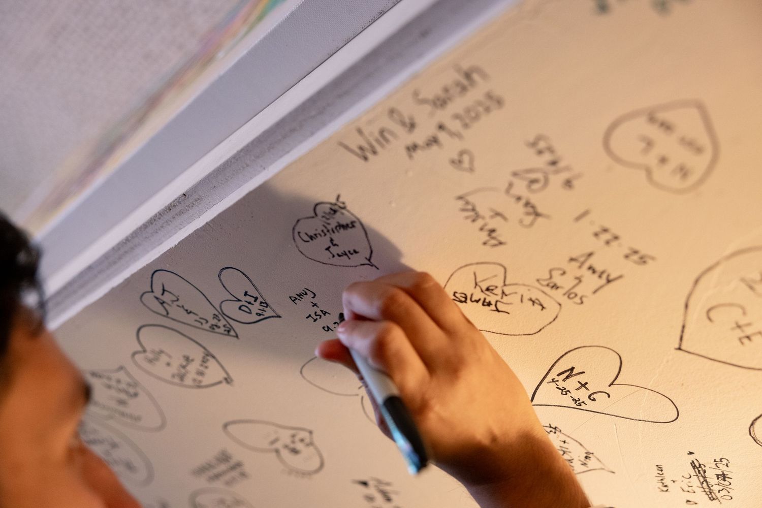 Close-up view of someone writing mathematical equations and sketches on white paper with a blue pen.