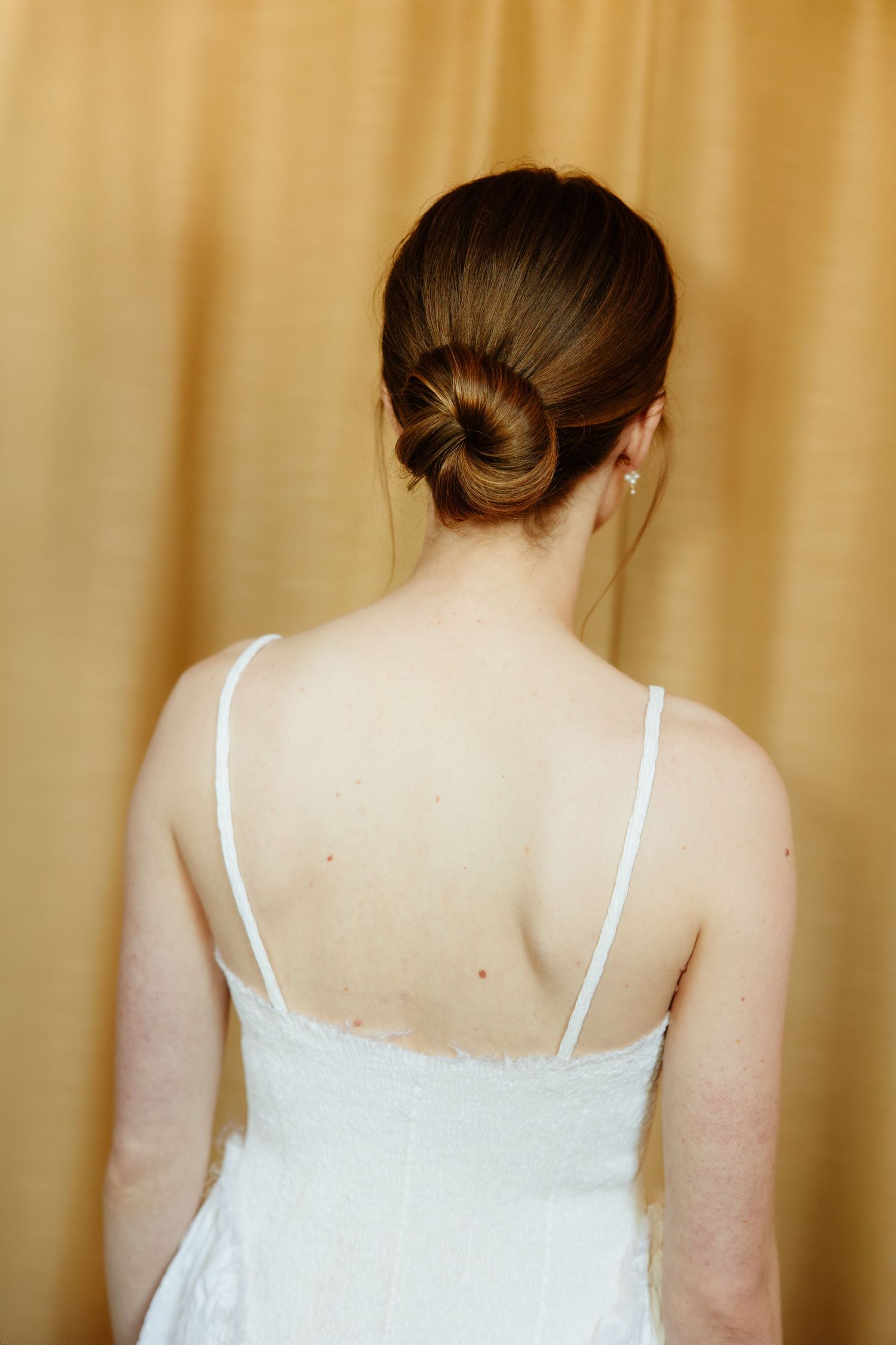 Series of photos showing back views of a white lace wedding dress with thin spaghetti straps against beige background.