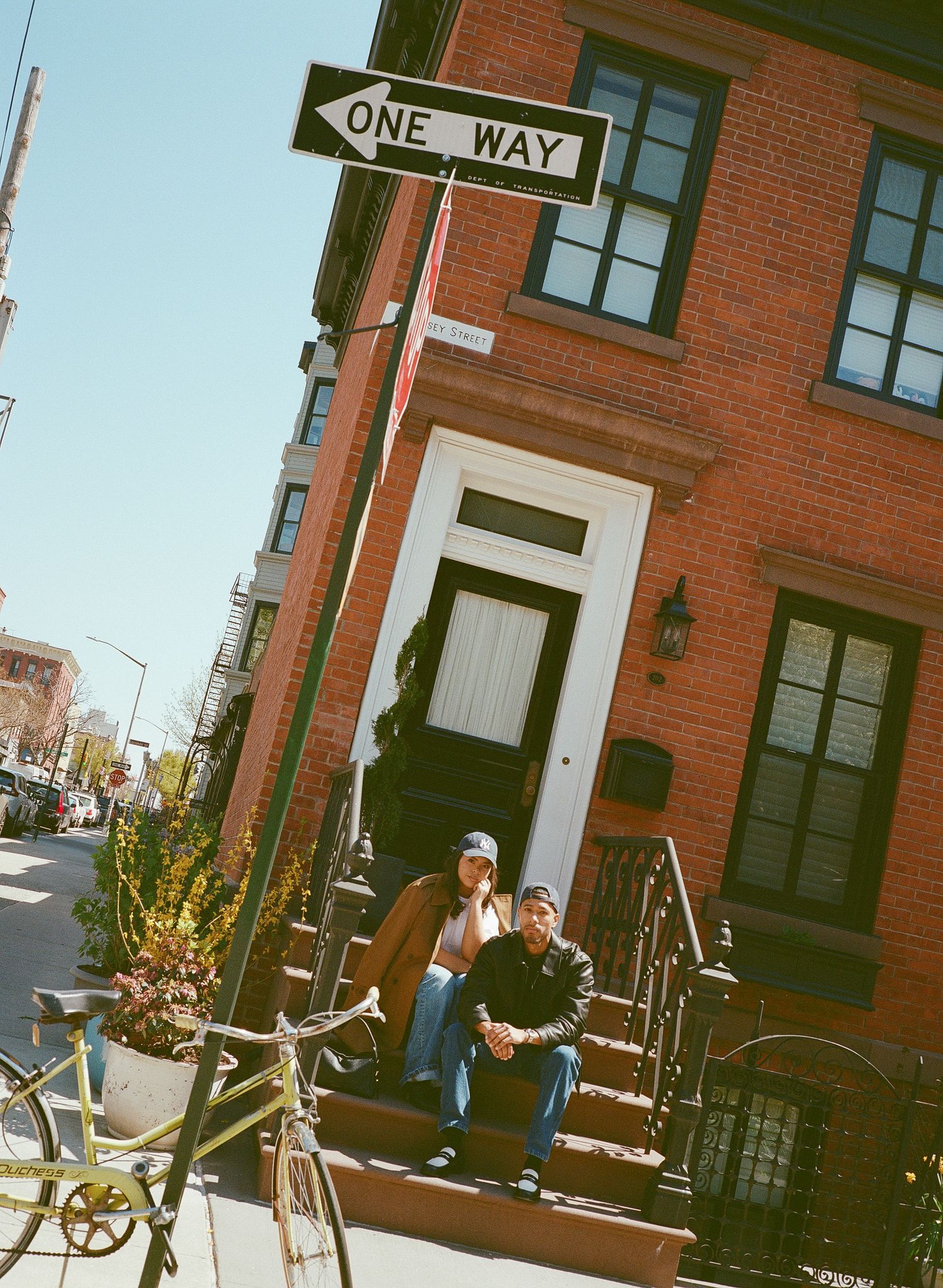 A panoramic view of a brick building street corner with a one-way sign and bicycles parked along the sidewalk.