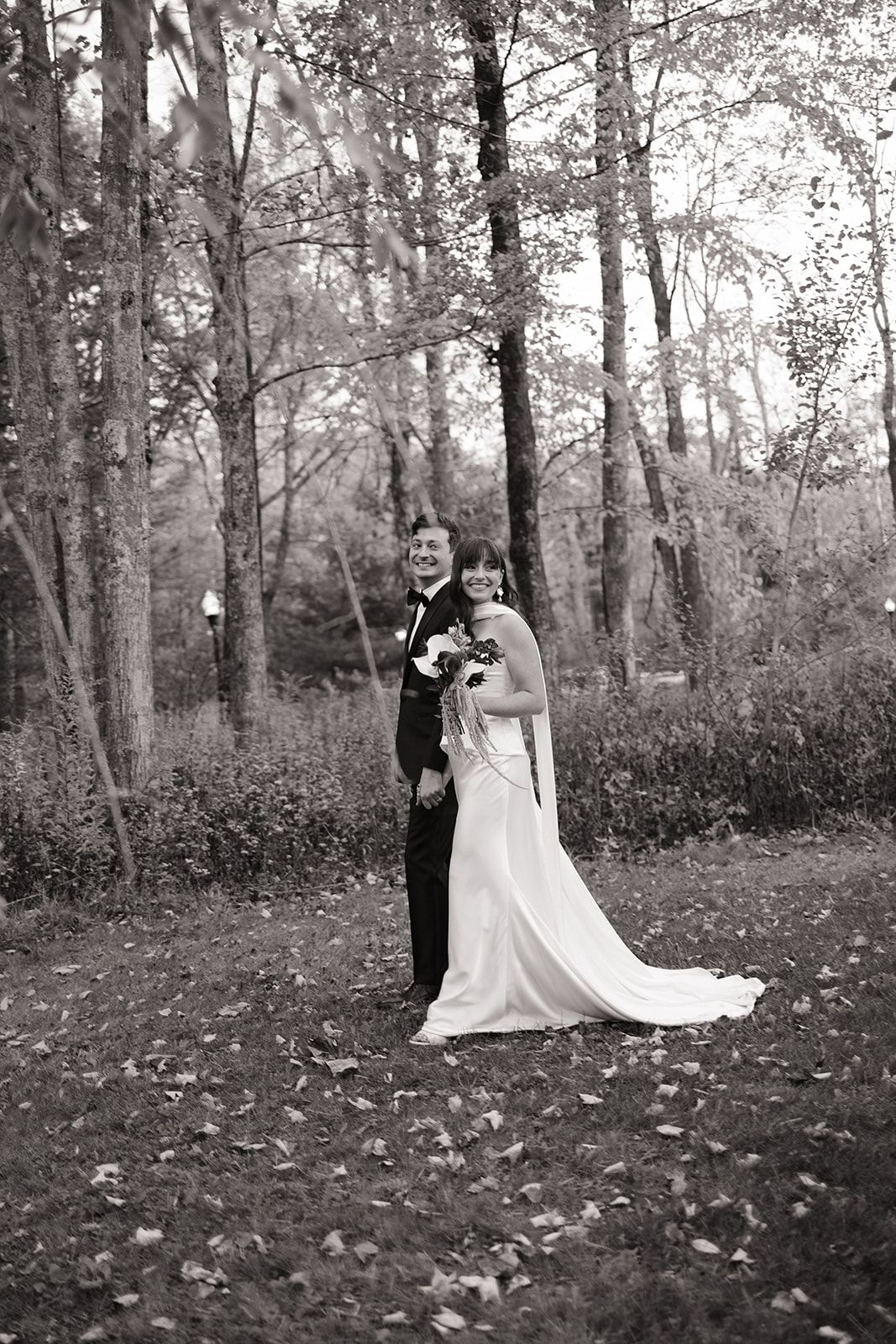 Black and white wedding photos showing playful moments between a couple in a wooded outdoor setting.