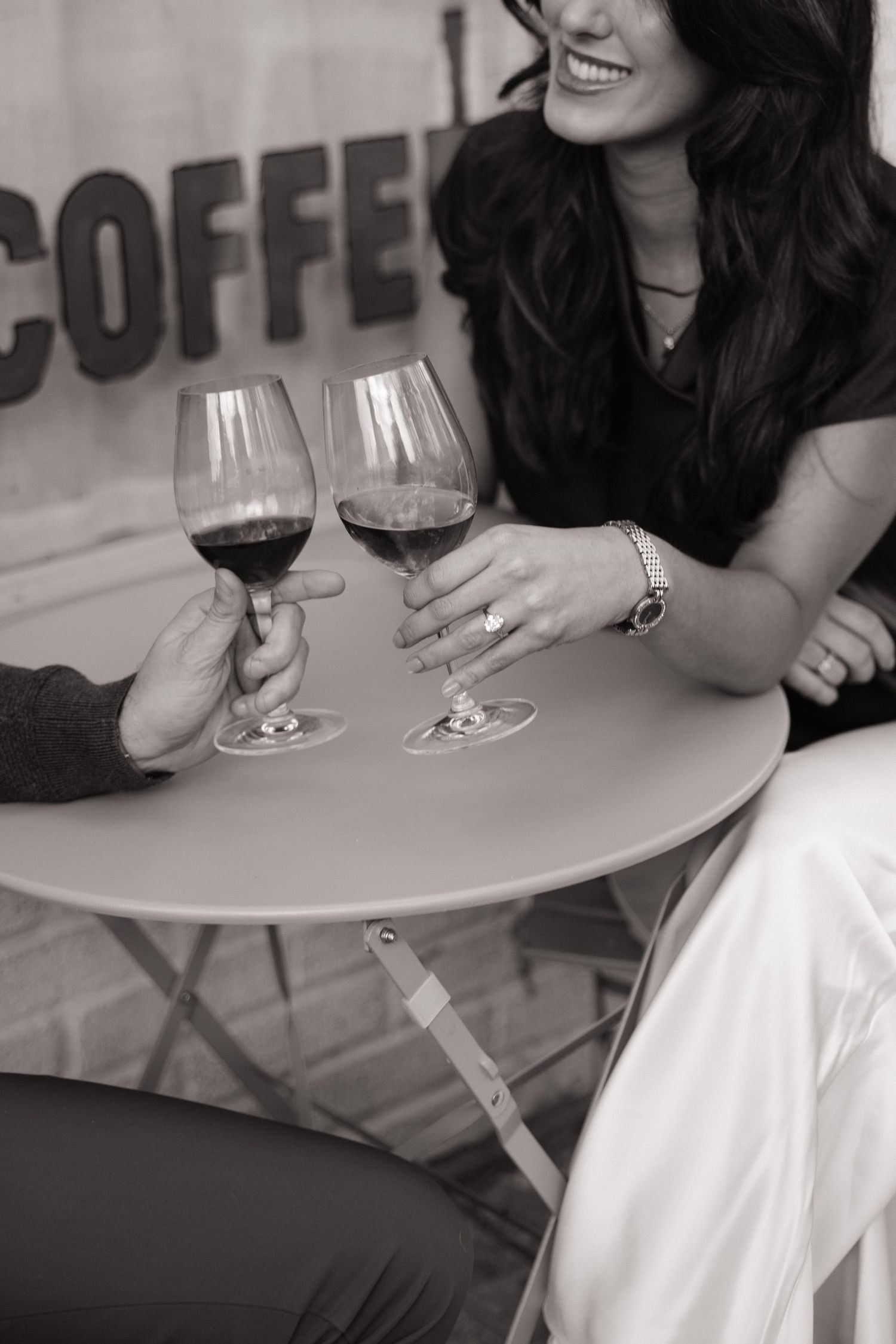 Two people enjoying glasses of red wine at an outdoor cafe table.