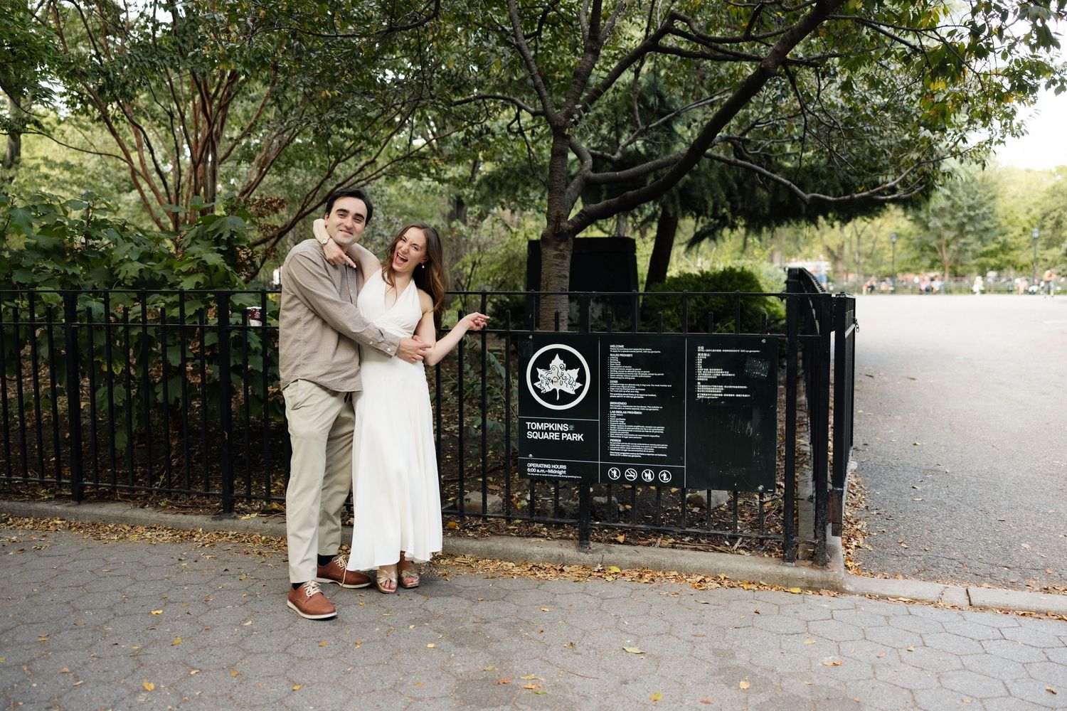 A romantic wedding couple shares a tender moment in front of a black iron gate at an outdoor venue.