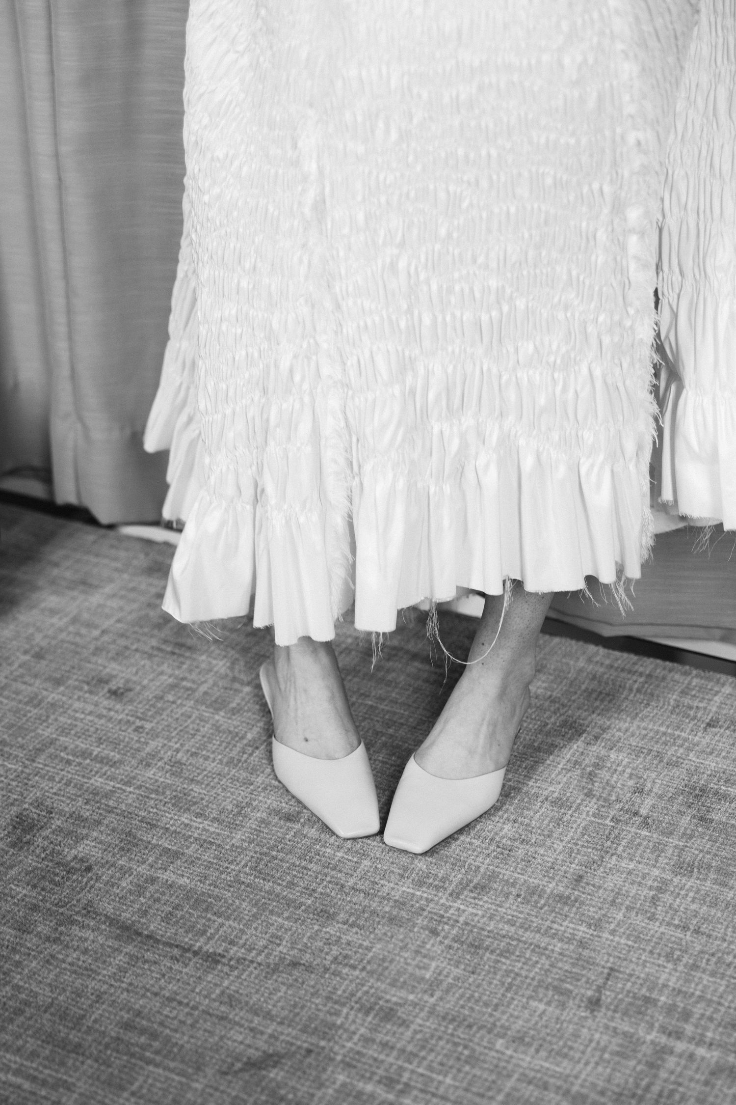 A sequence of black and white photos showing white dress hemlines and shoes on a textured carpet floor.