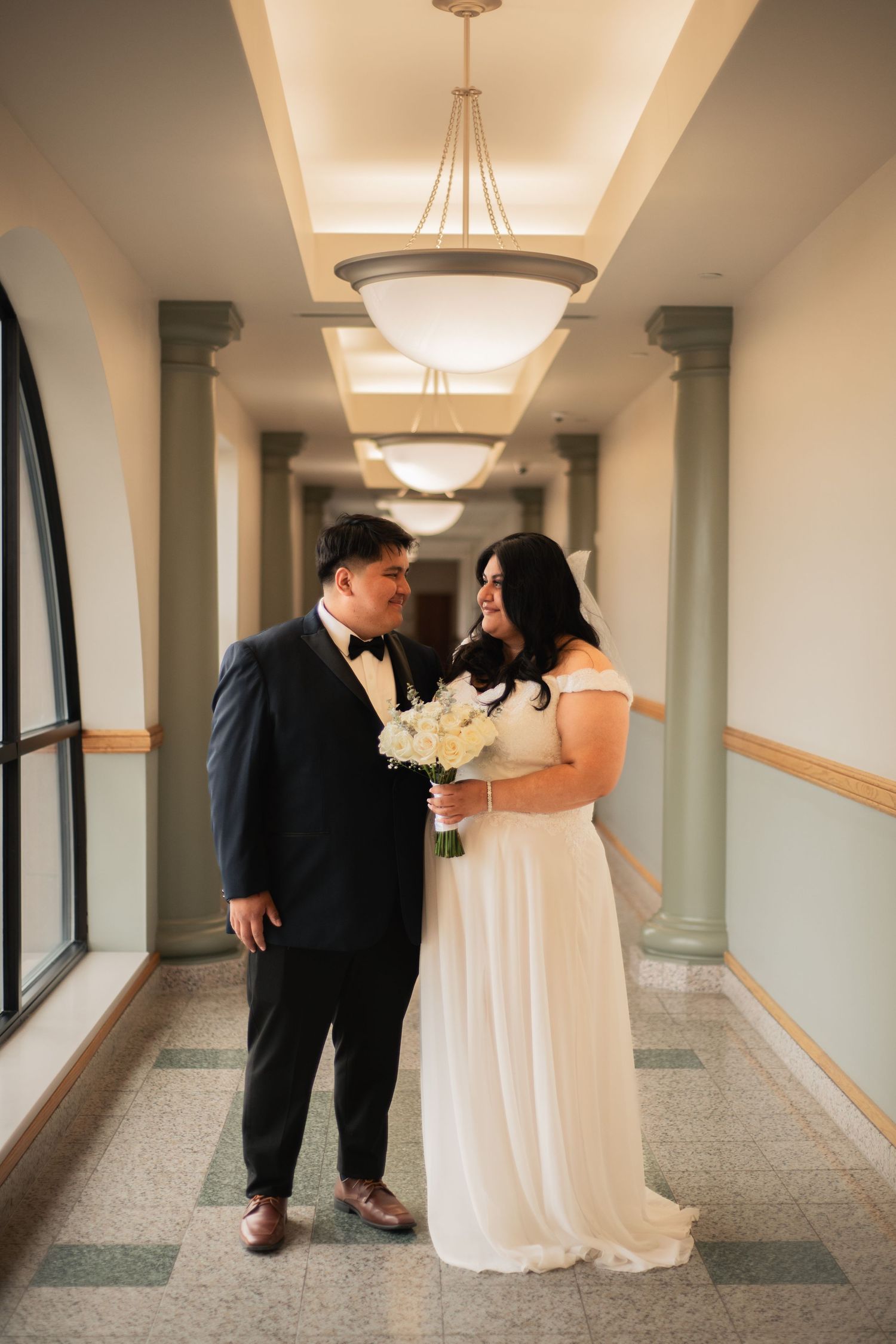 Couple looking at each other at Champaign County Courthouse wedding in Urbana Illinois with columns in background taken in spring.