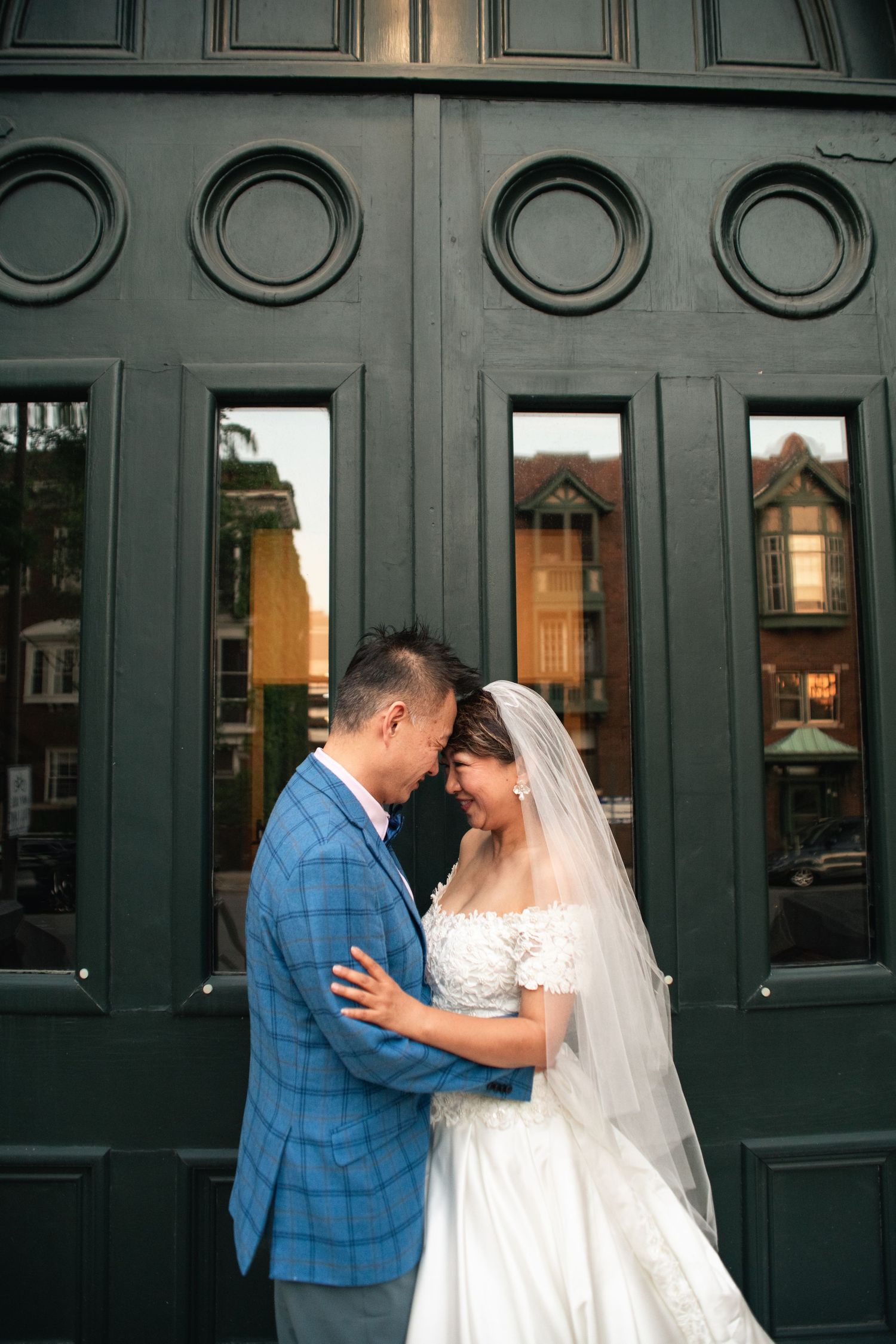 Cinematic wedding style anniversary photo of couple in front of Champaign, IL church doors with golden hour reflection of nearby buildings