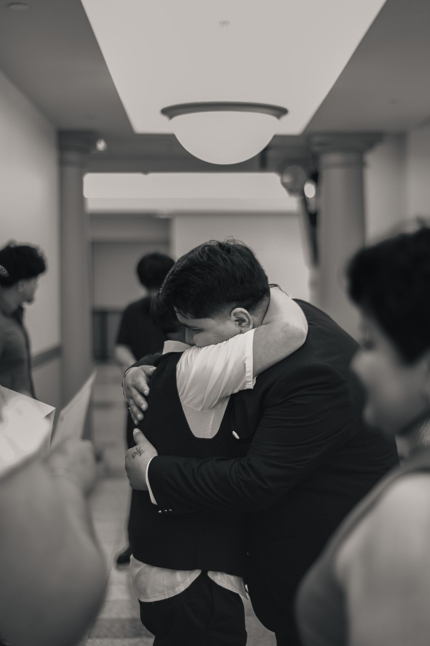Cinematic style candid mother son hug after spring wedding at Champaign County Courthouse in Urbana, IL by Urbana Ever After Photography