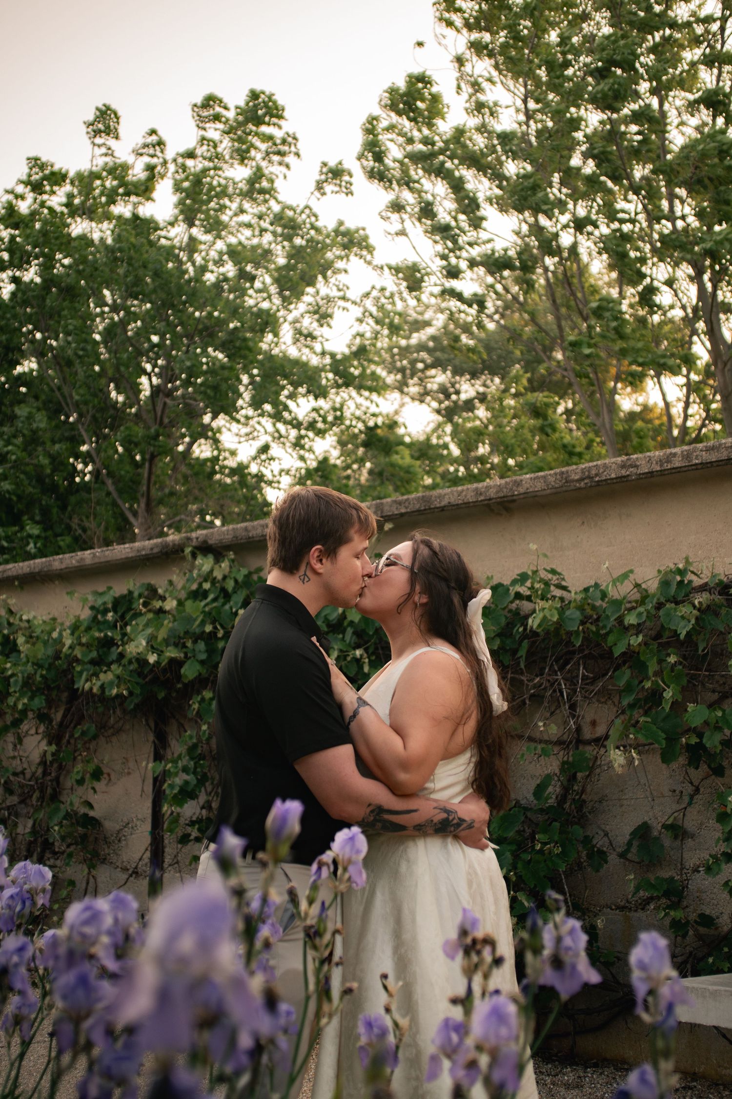 Engagement photo, couple kissing under backlit golden hour light in the peony garden at Allerton Park and Retreat Center in Monticello, IL