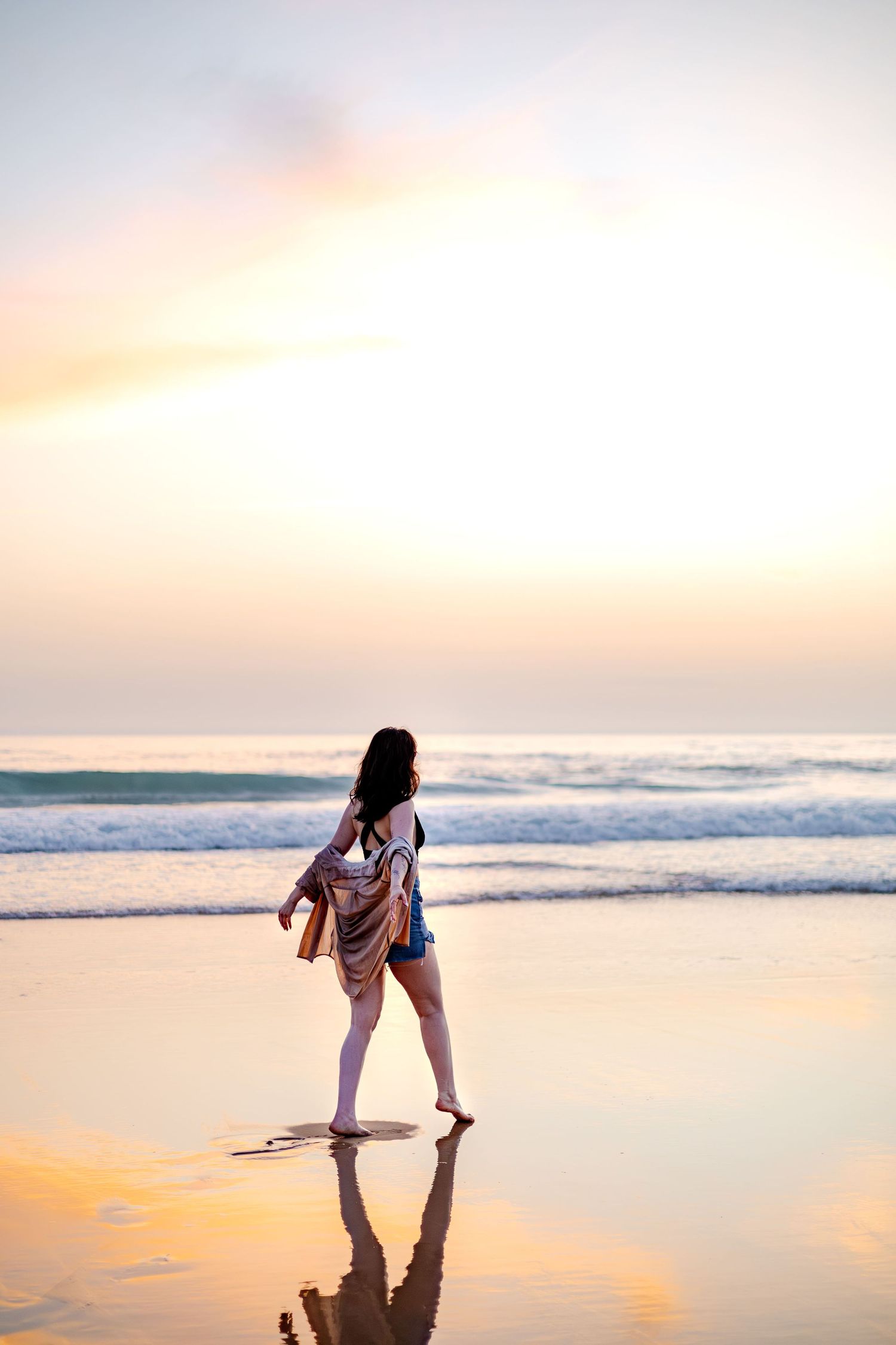 Femme qui marche dans le sable à l'océan au coucher du soleil. Séance photo maternité en extérieur à Langon, La Réole Sud Gironde