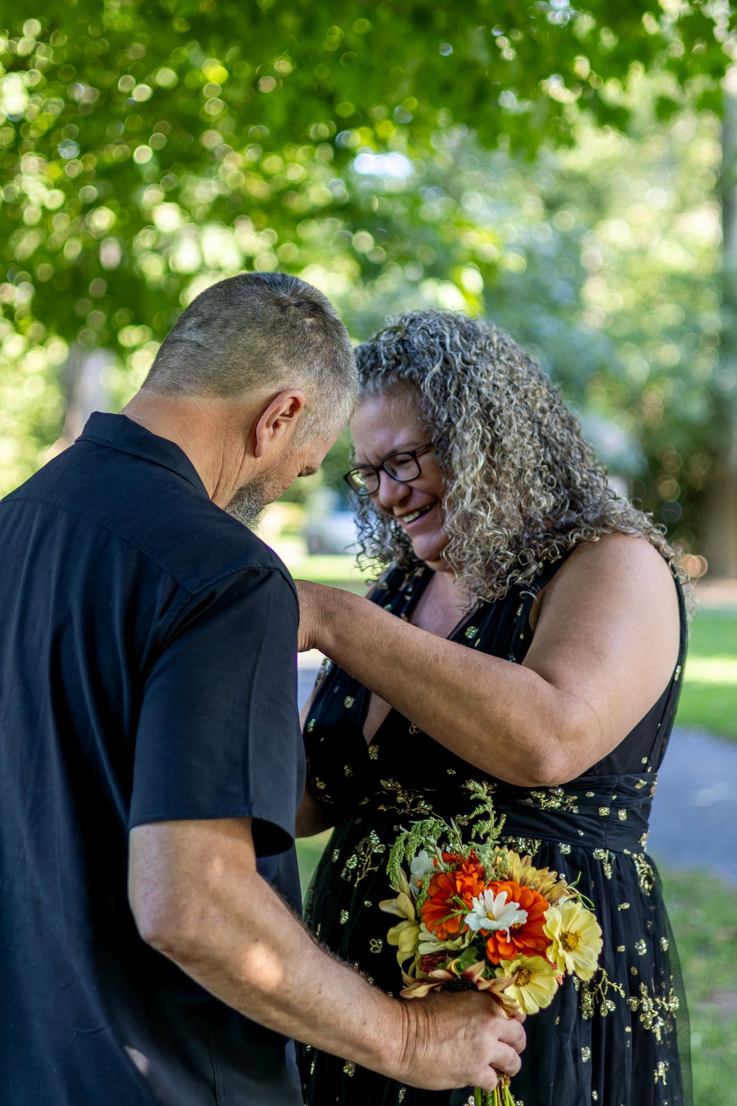 Couple shares tender moments during outdoor photo session with vibrant floral bouquet.