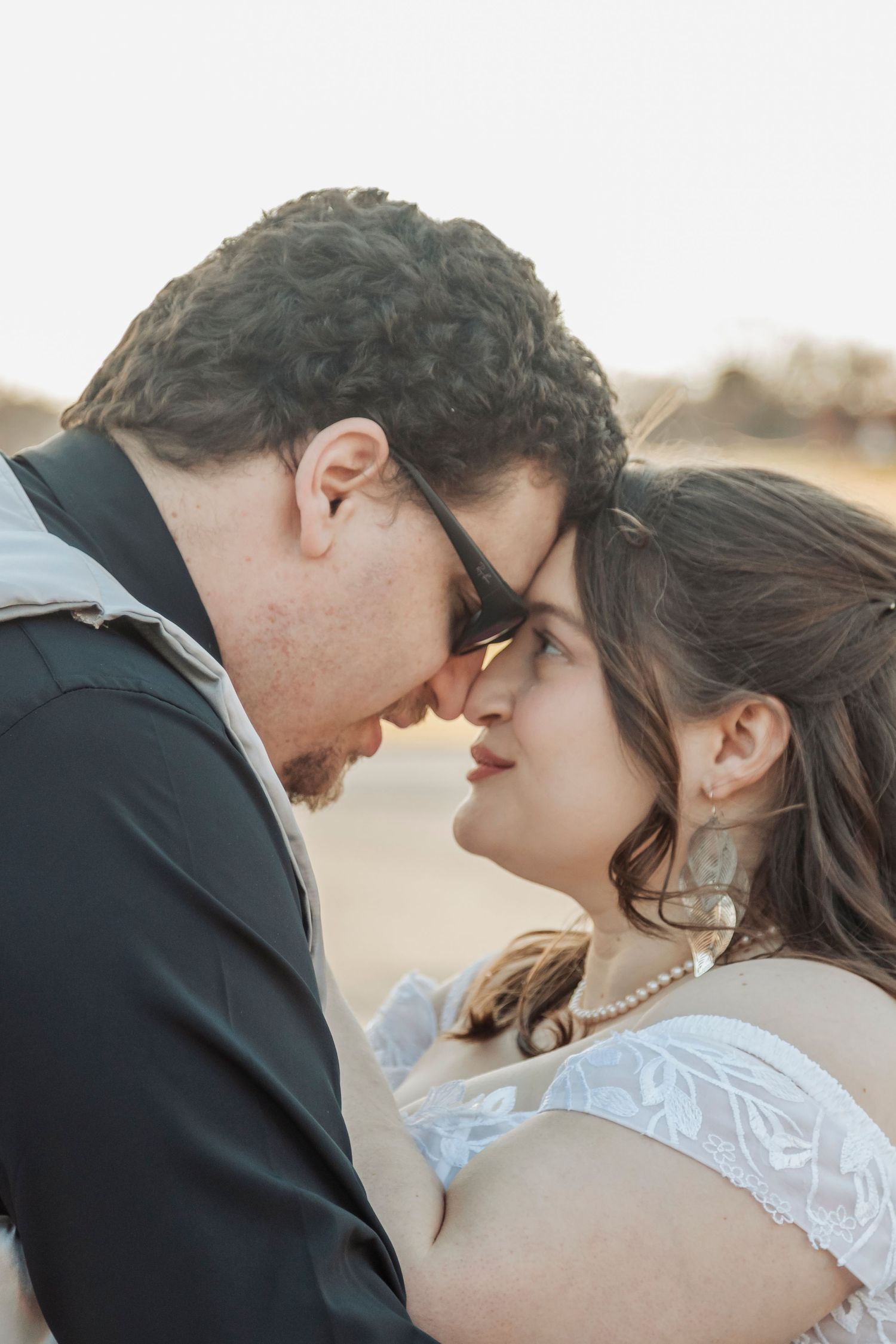 Romantic couple in wedding attire sharing an intimate moment at sunset.