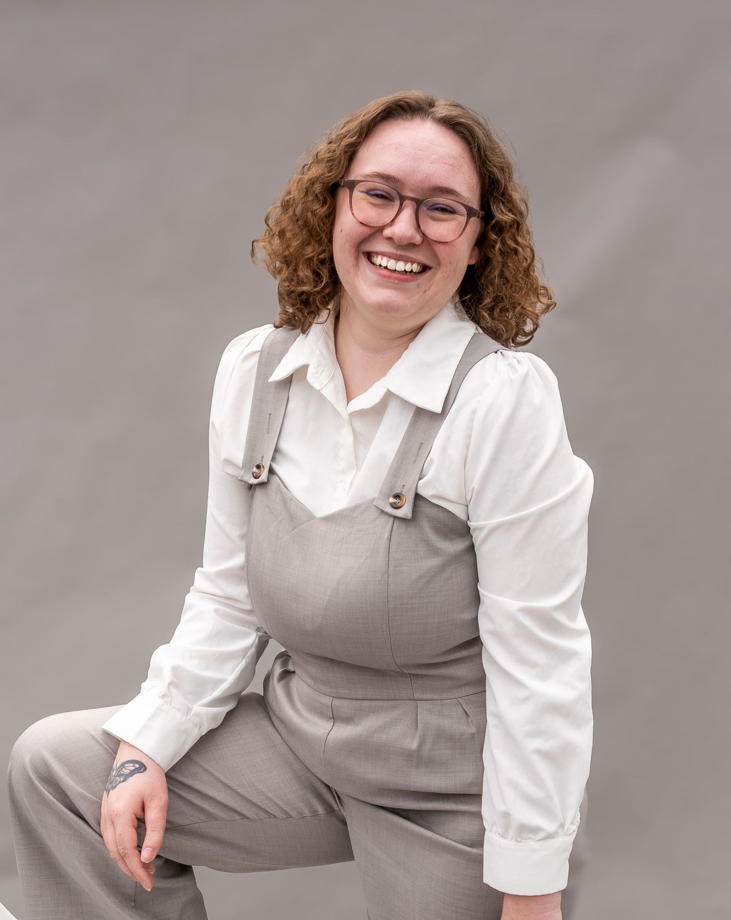 Business professional headshots in a gray vest and white blouse against neutral backdrop.