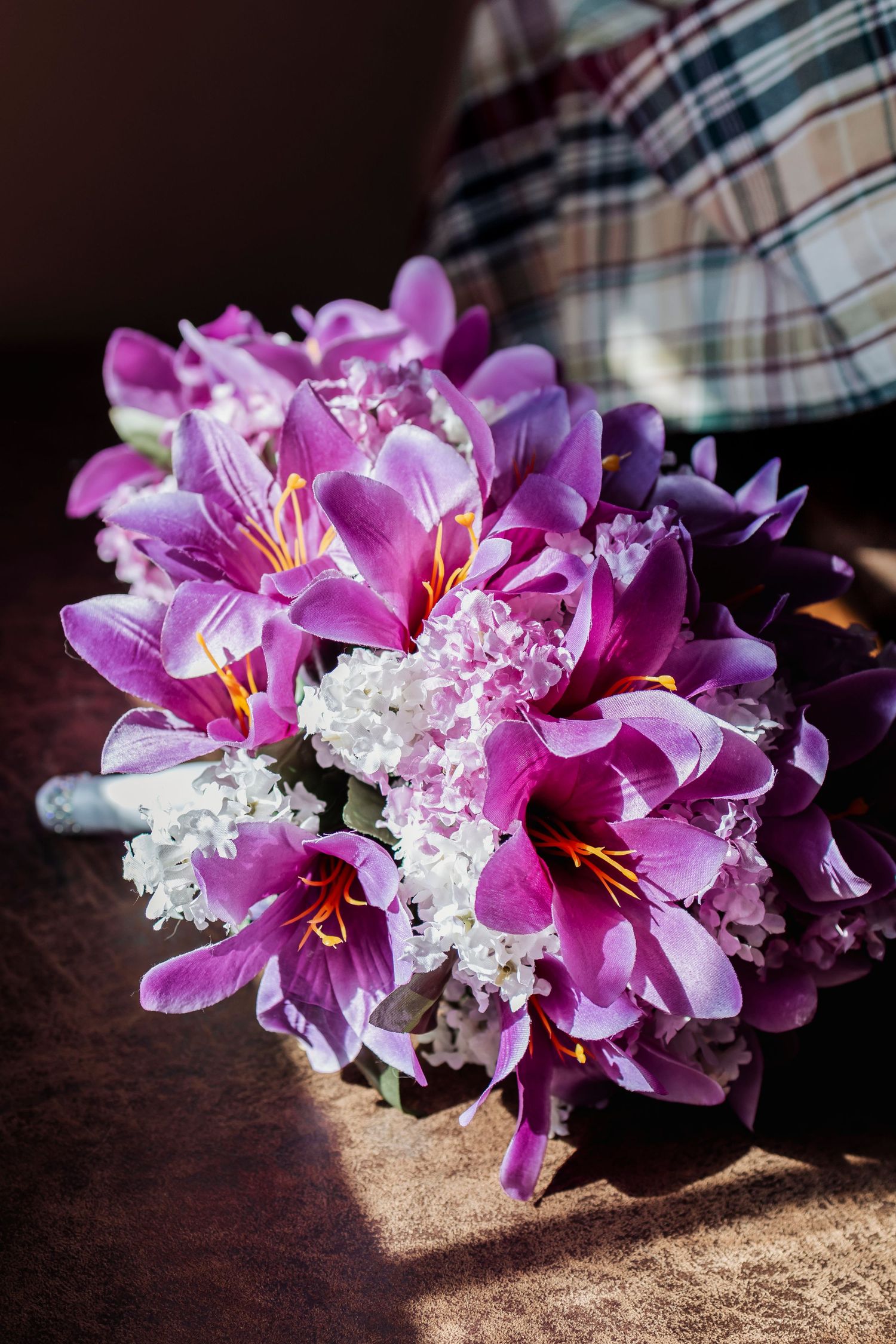 Beautiful purple lilies arranged with delicate white baby's breath flowers on a dark surface.