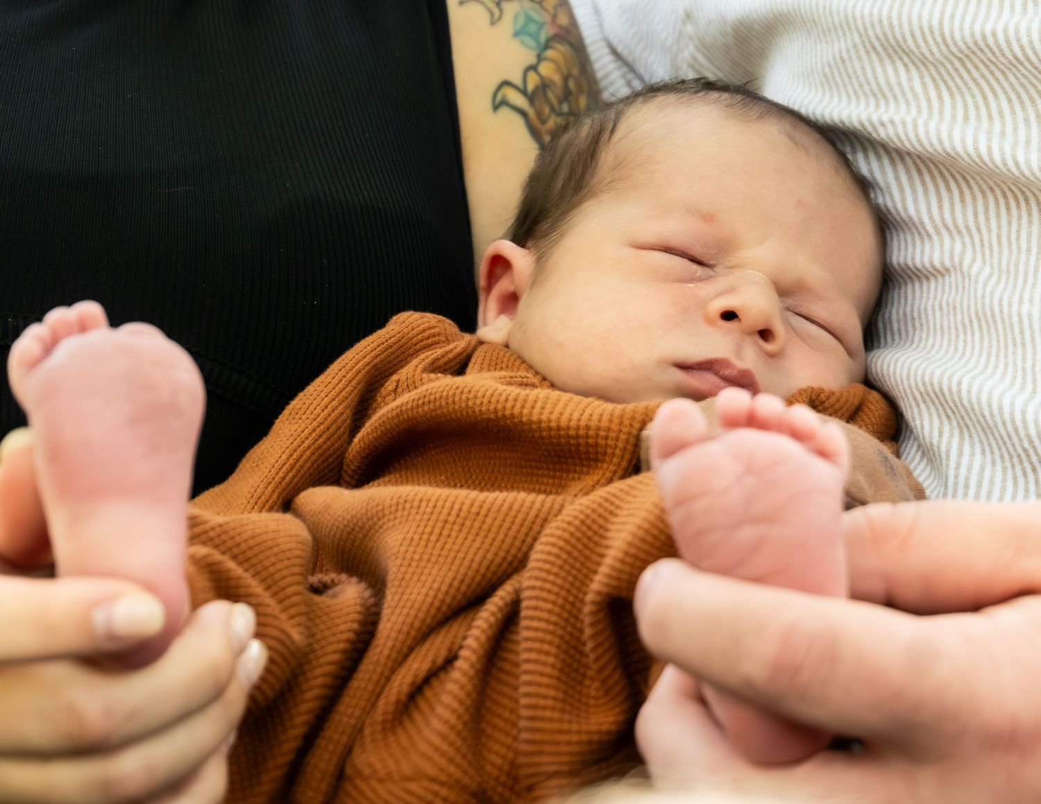 Close-up view of a sleeping baby wearing a brown knit outfit.